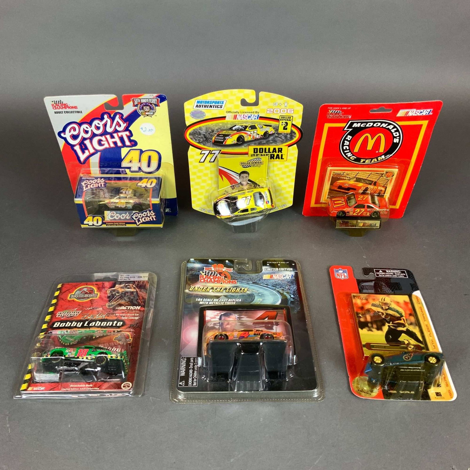A Collection of Six NASCAR Model Cars and NFL Die-Cast Collectibles 1:64 Scale: This lot consists of six 1:64 scale die-cast collectible vehicles and associated sports memorabilia, primarily focused on NASCAR with one NFL inclusion. All items are contained within their original