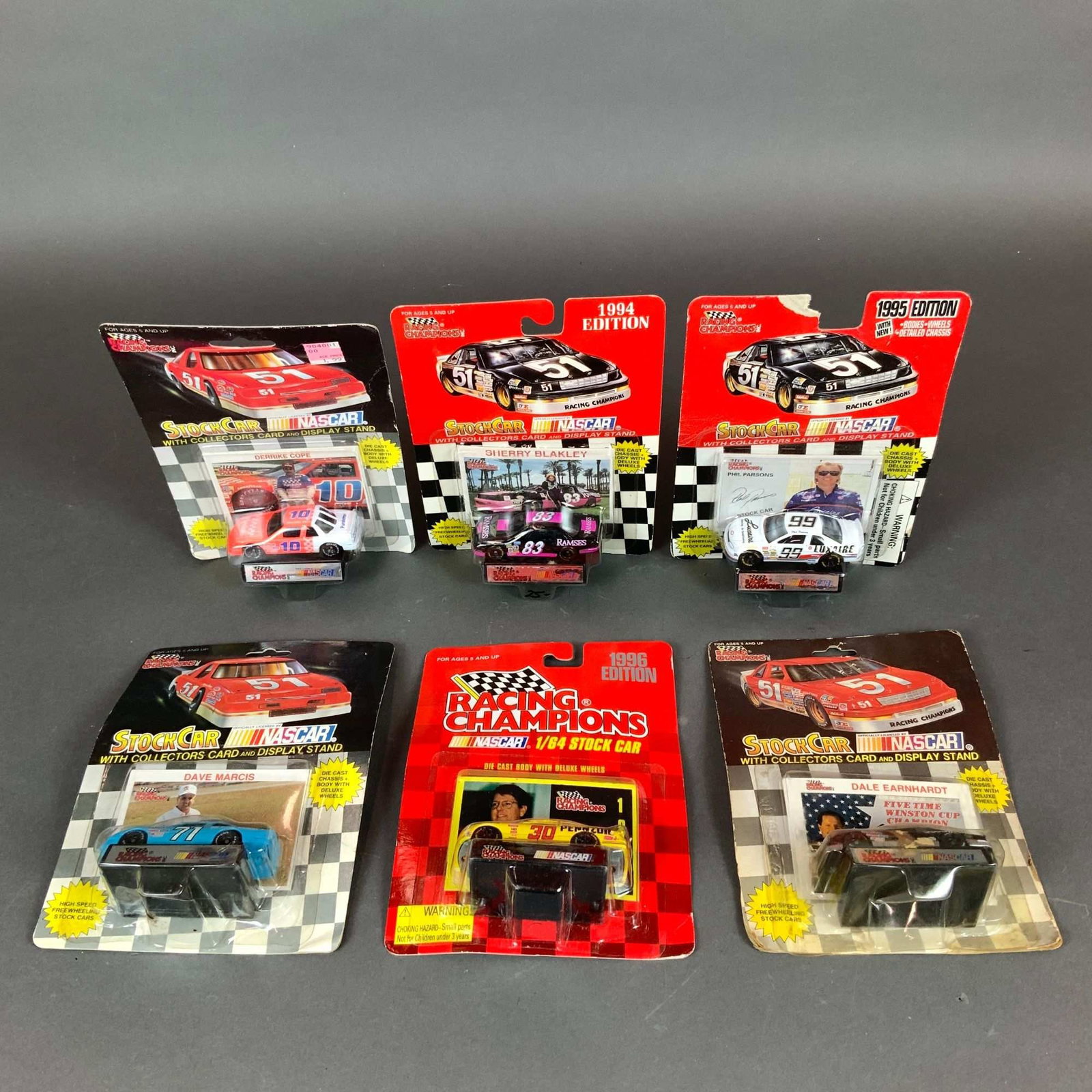Six Racing Champions NASCAR 1/64 Die-Cast Stock Cars: This lot consists of six Racing Champions 1/64 scale NASCAR die-cast stock cars in their original blister pack packaging. Each set includes a die-cast vehicle, a collector card, and a black plastic