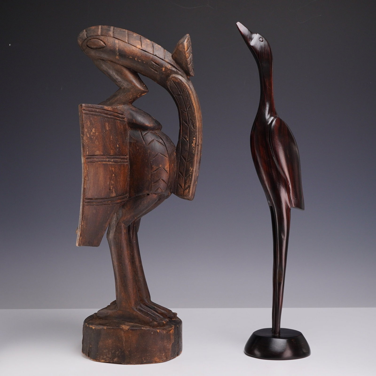 Two Carved Wooden Bird Sculptures including a Senufo Hornbill: This lot consists of two carved wooden bird sculptures representing distinct artistic traditions. The first is a Senufo Porpianong figure, also known as a Sejen or hornbill, originating from the Senuf