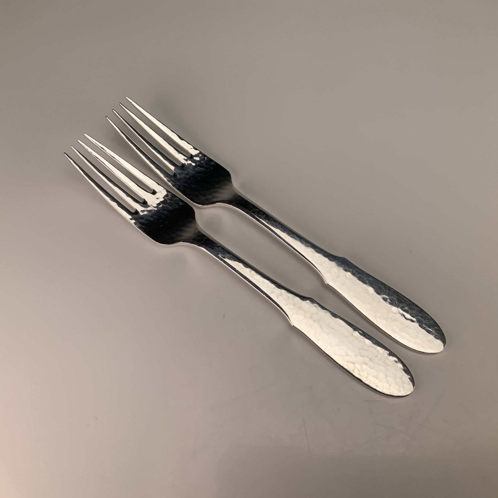 A Pair of Georg Jensen Denmark Mermaid Pattern Hammered Silverplate Forks: This pair of forks is identified as the Mermaid pattern by Georg Jensen, Denmark. The items are manufactured from silver-plated nickel silver, indicated by the EPNS designation. The design features a 