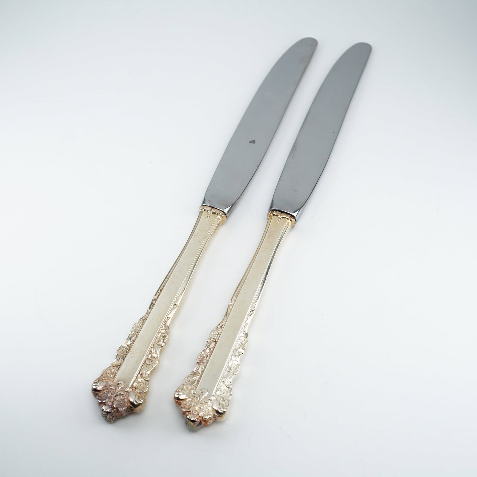 2pc Lunt Sterling Silver and Stainless Steel Dinner Spreaders, Belle Meade: A refined pair produced by Lunt Silversmiths during the 1967??"1997 period, executed in the Belle Meade pattern. The sterling silver handles display detailed Rococo-inspired scrollwork with raised flo