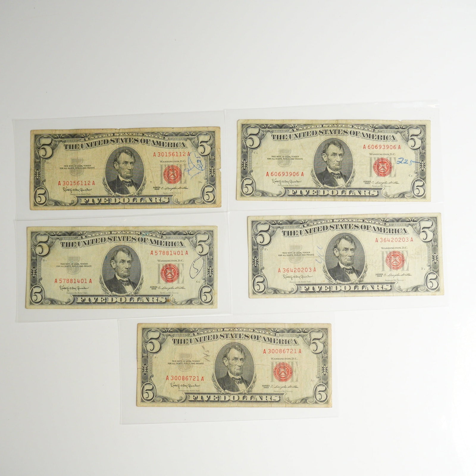 Five 1963 US Five Dollars Red Seal Notes: A collection of five United States Notes, denomination five dollars, from Series 1963. These banknotes are distinguished by their red Treasury seals and red serial numbers. The obverse of each note fe