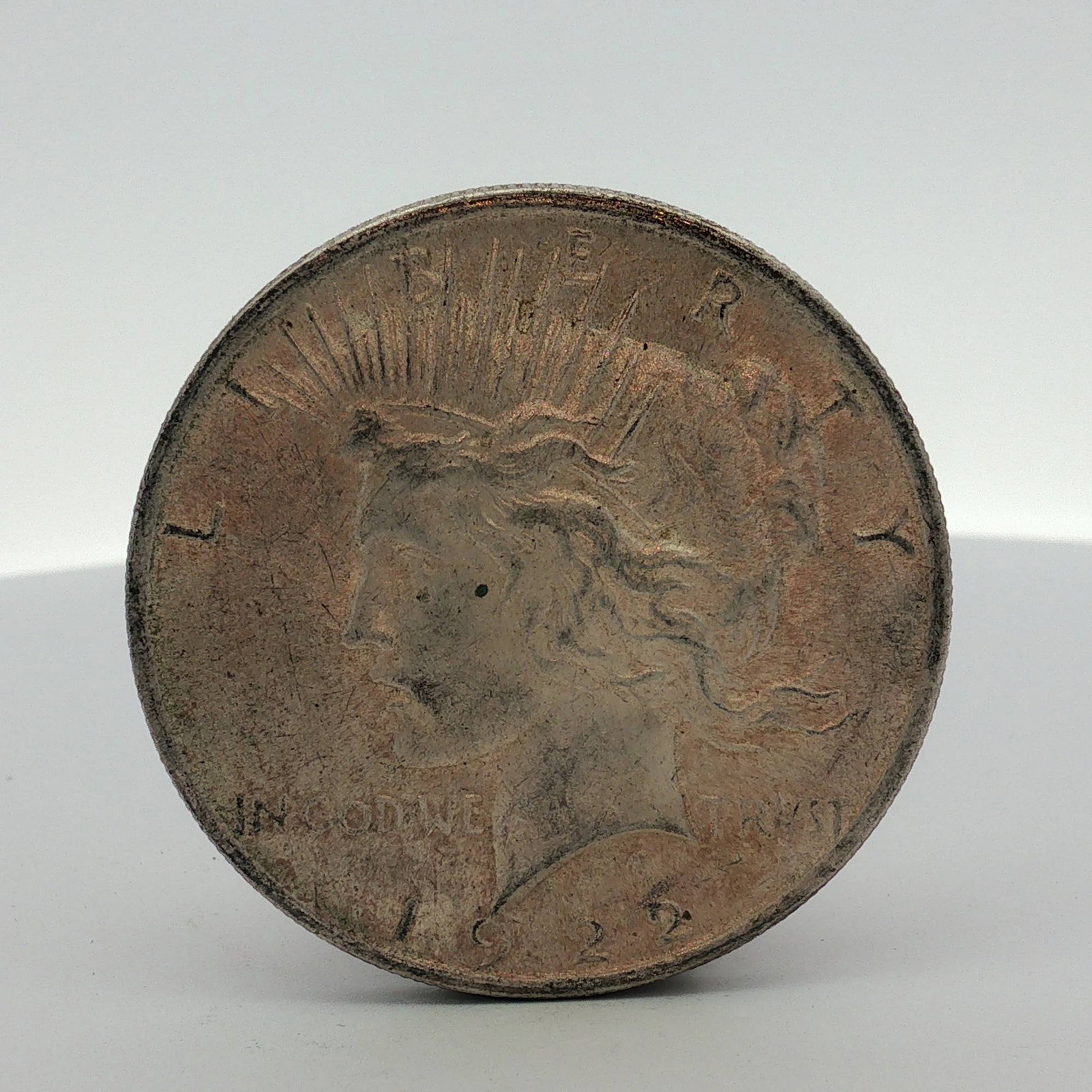 1922 US Peace Silver Dollar: This 1922 US silver Peace dollar was struck at the Philadelphia Mint. The coin is composed of 90% silver and 10% copper with a reeded edge. The obverse displays the date 1922 and the mottoes LIBERTY