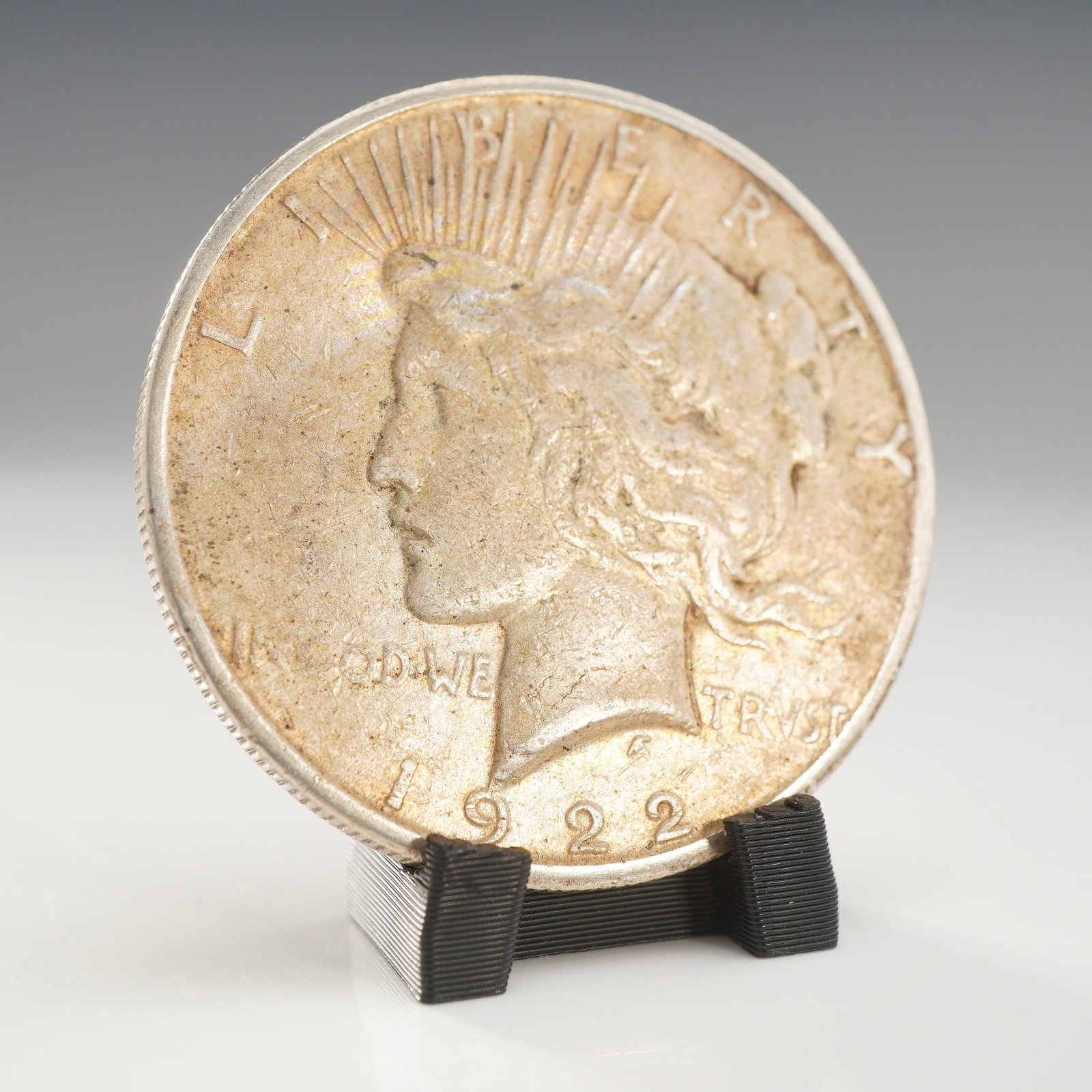 1922-S US Peace Silver One Dollar Coin, Circulated: A United States 1922 Peace Silver Dollar, minted at the San Francisco Mint. The coin is composed of 90% silver and 10% copper. It features the standard Peace Dollar obverse and reverse designs by
