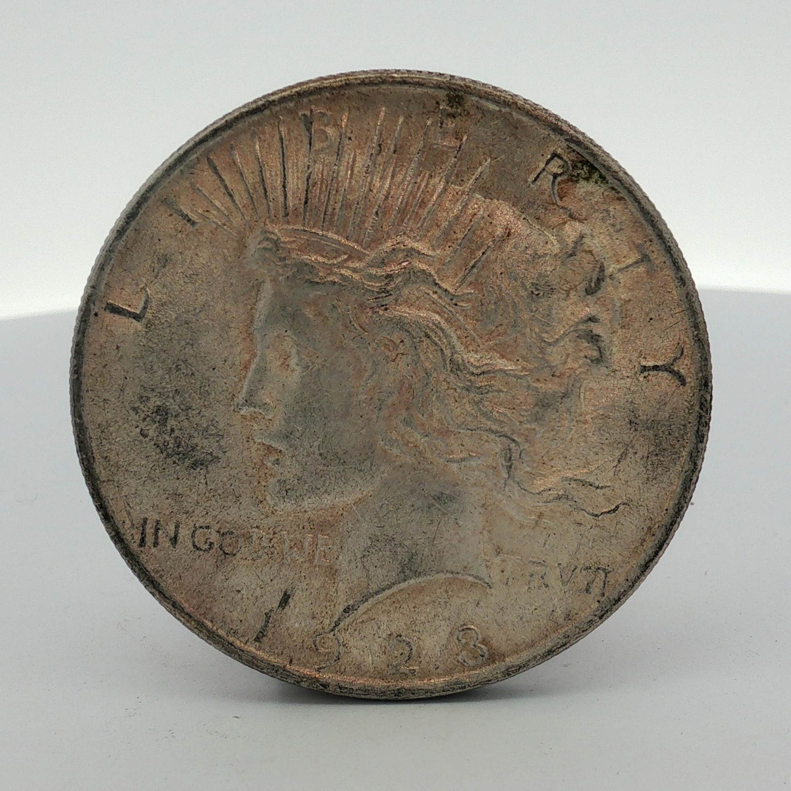 1923 US Peace Silver Dollar: This 1923 US Peace silver dollar is a circulating silver coin struck by the US Mint. The obverse features the Peace dollar design by Anthony de Francisci, including the inscriptions LIBERTY, IN GOD
