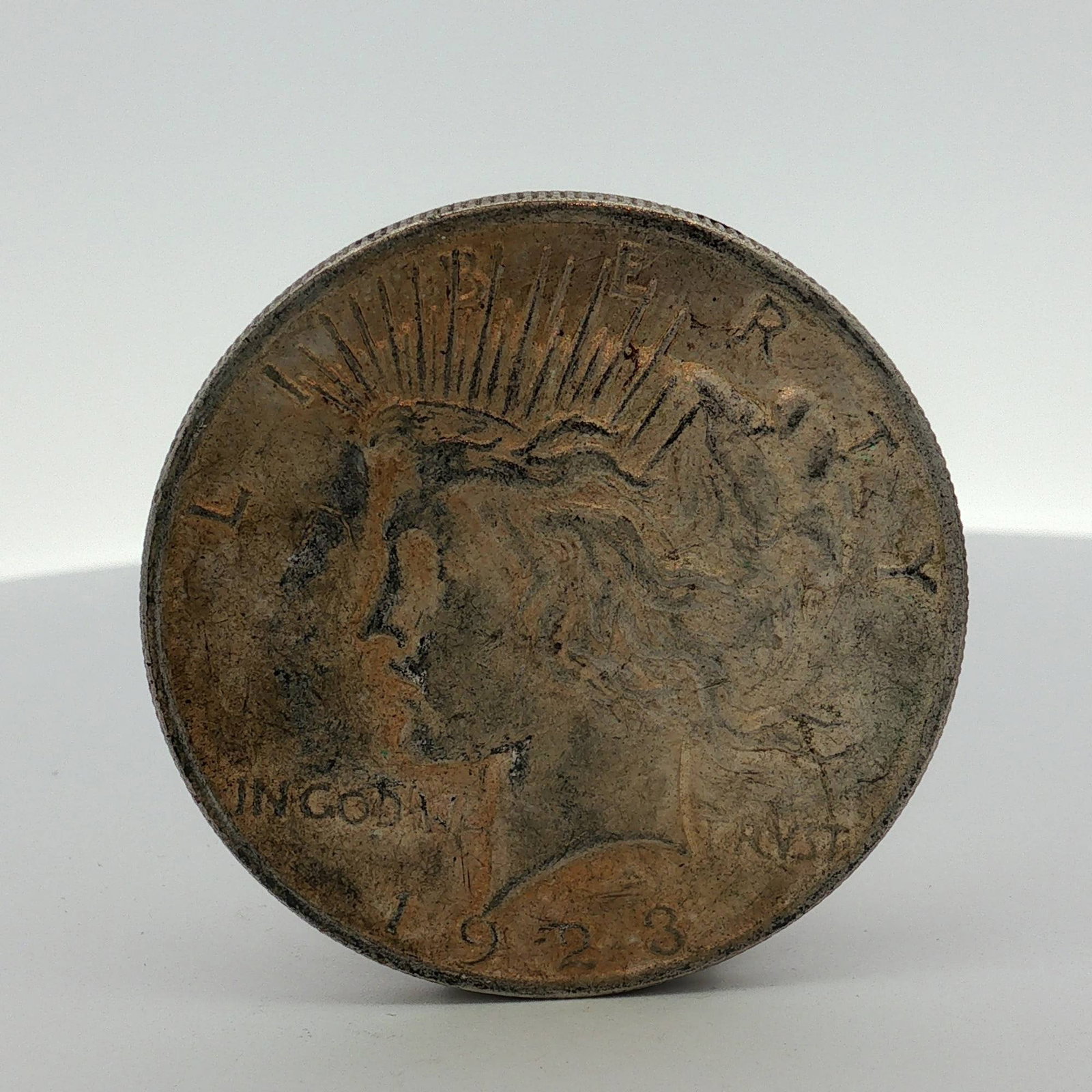 1923 US Silver Peace Dollar: A 1923 US silver dollar of the Peace design, struck at the Philadelphia mint. The coin is composed of 90% silver and 10% copper with a reeded edge. The obverse features the Peace dollar Liberty head