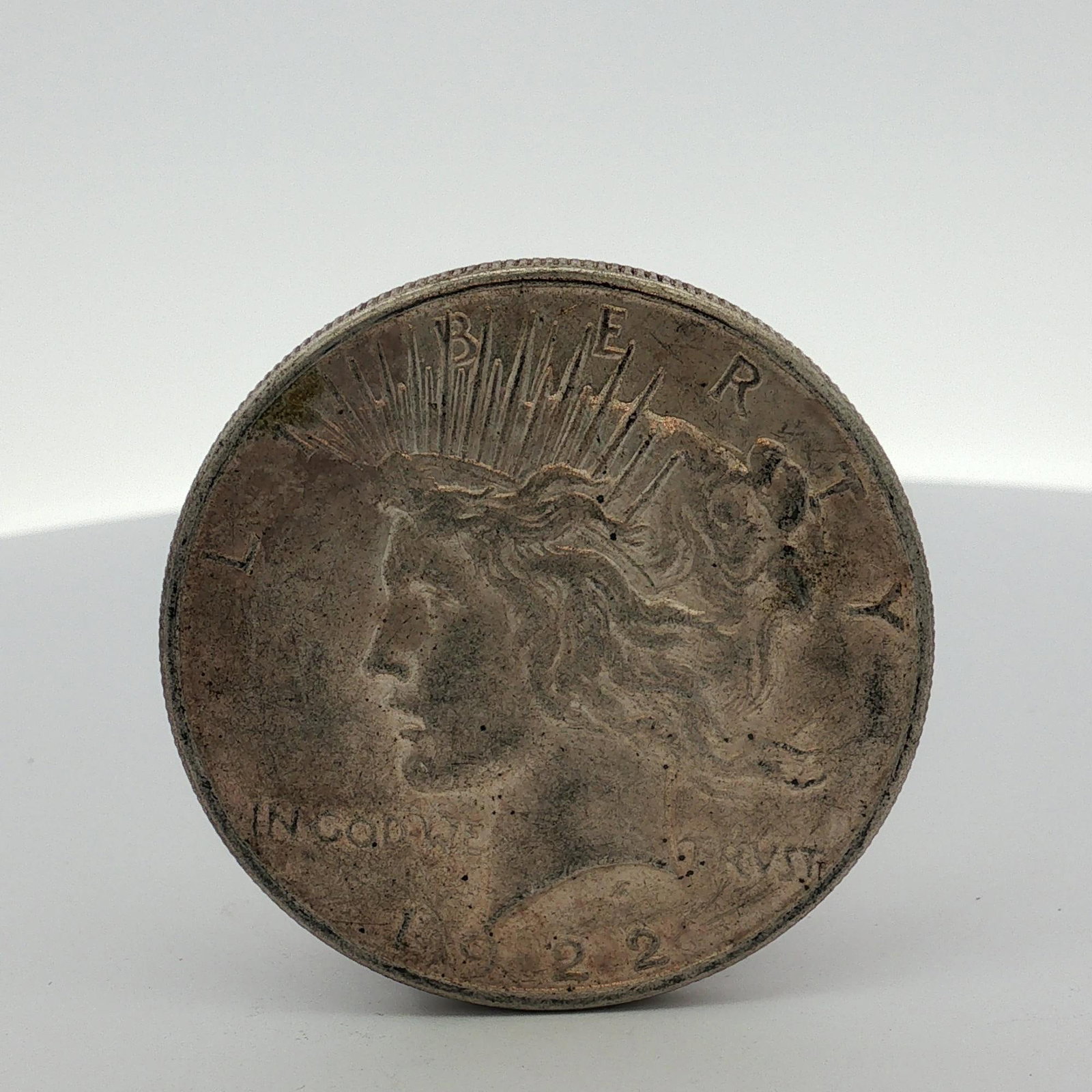 US 1922 Peace Silver Dollar: This US 1922 Peace silver dollar was struck at the Philadelphia Mint. The obverse features the Peace Dollar type design with inscriptions L I B E R T Y, IN GOD WE TRVST, and the date 1922. The