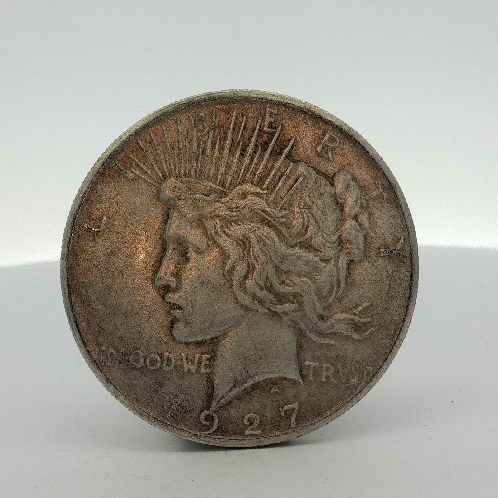 US 1927 Peace Silver Dollar: US 1927 Peace silver dollar, struck at the Philadelphia Mint. This specimen is composed of .900 fine silver. It features the standard Peace dollar obverse and reverse types. The designer's initials