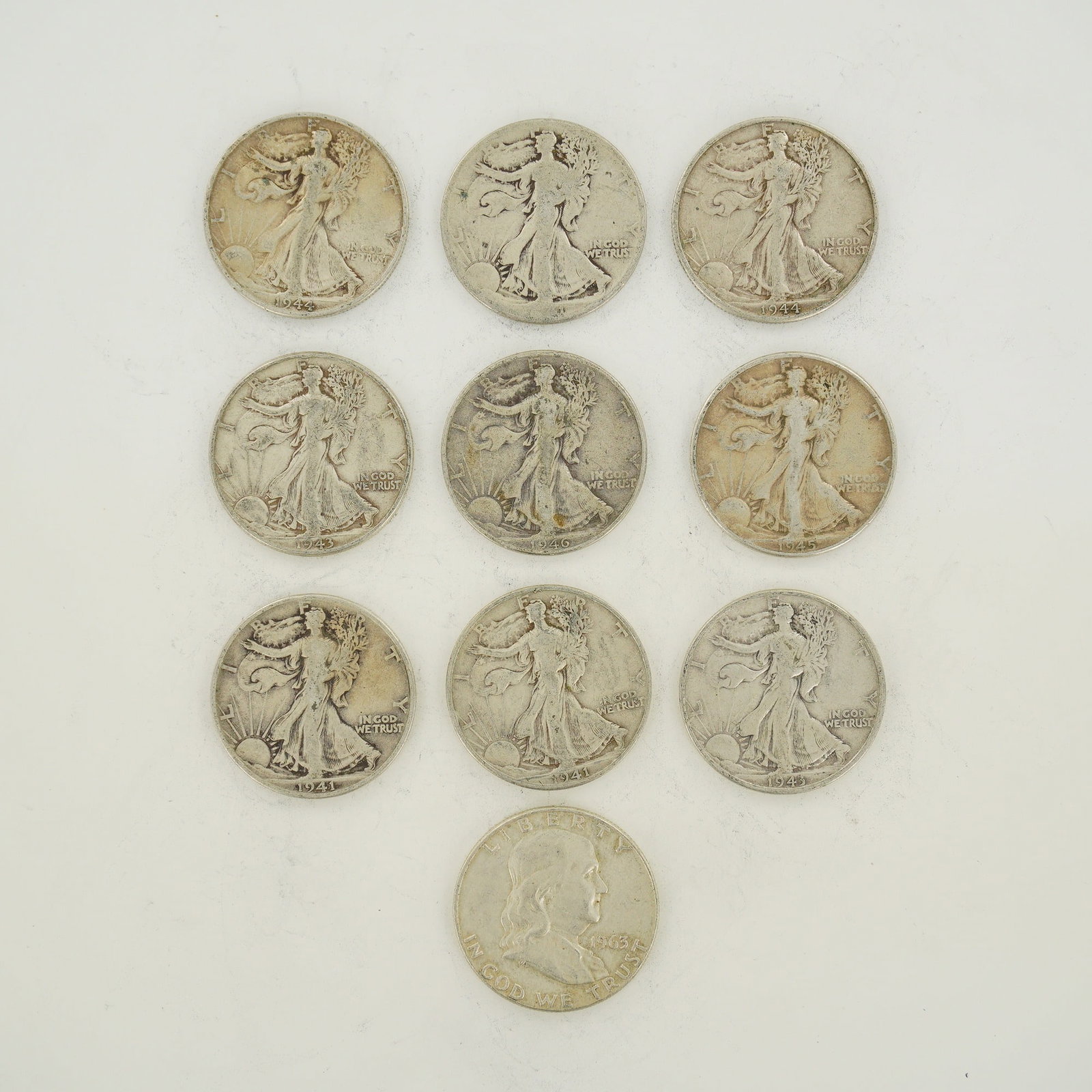 A Collection of 10 US Silver Half Dollars, Walking Liberty and Franklin Types: A collection of 10 US silver half dollars, primarily consisting of the Walking Liberty type with one Franklin type coin. The Walking Liberty coins include dates 1941, 1943, 1944, 1945, and 1946, with 