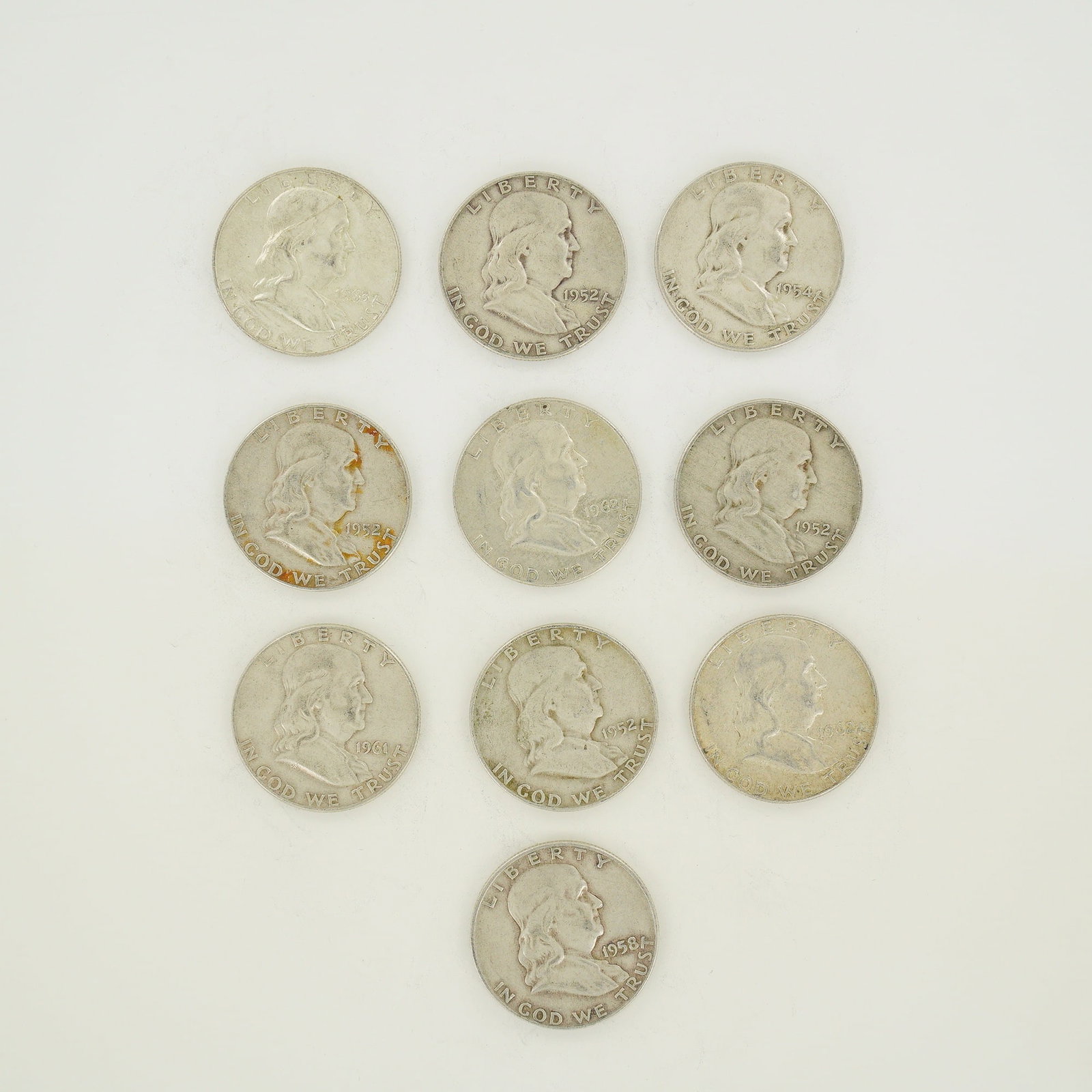 A Collection of Ten US 90 Percent Silver Franklin Half Dollars, $5.00 Face Value: A collection of ten US Franklin Half Dollars with a total $5.00 face value. These coins are struck in 90 percent silver. The group includes four 1952, one 1954, one 1958, one 1961, two 1962, and one 1