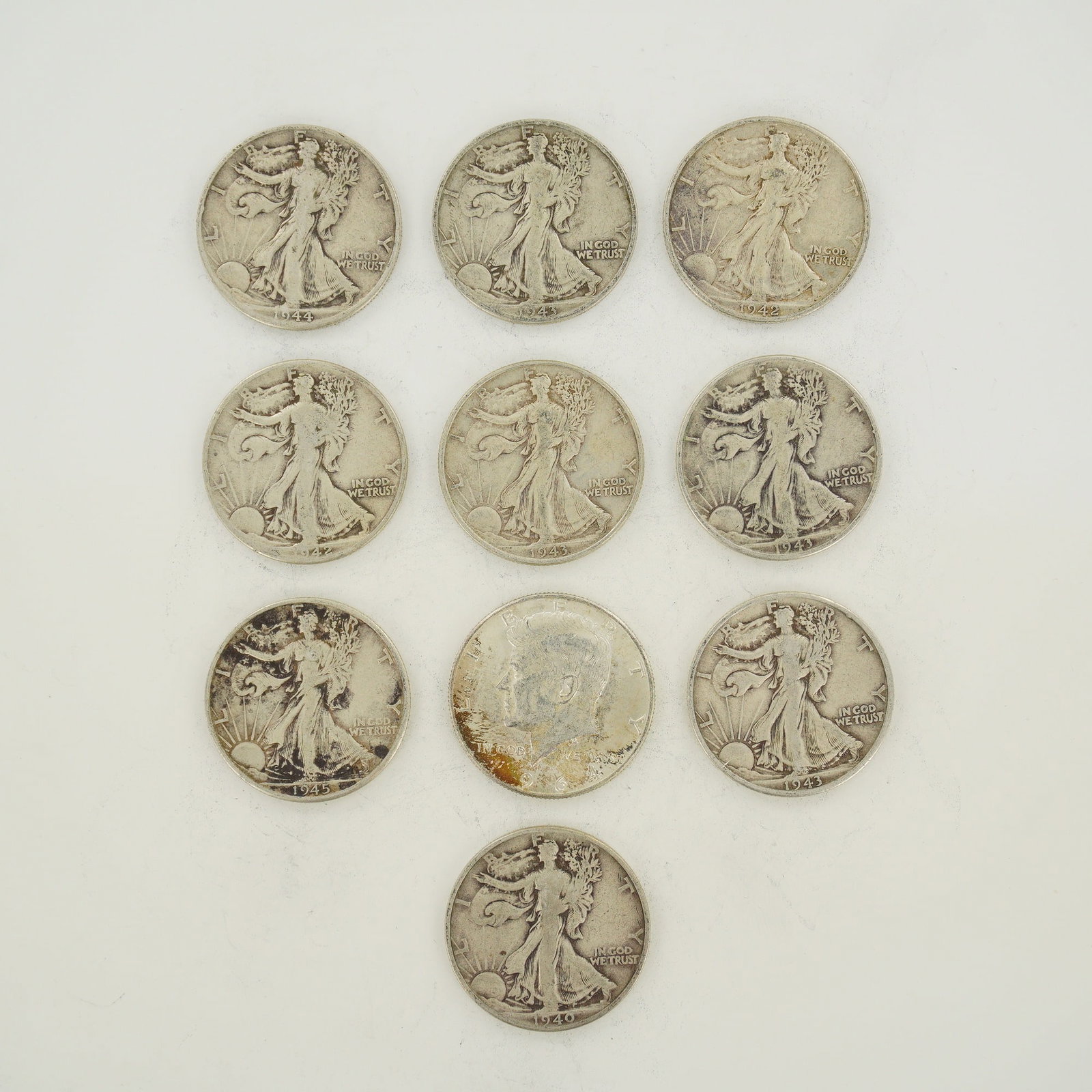 A Collection of US 90% Silver Mixed Date Half Dollars: A collection of US 90% silver half dollars including Walking Liberty and Kennedy types. This mixed date bag of coins contains examples dated 1940, 1942, 1943, 1944, 1945, and 1964. The coins represent