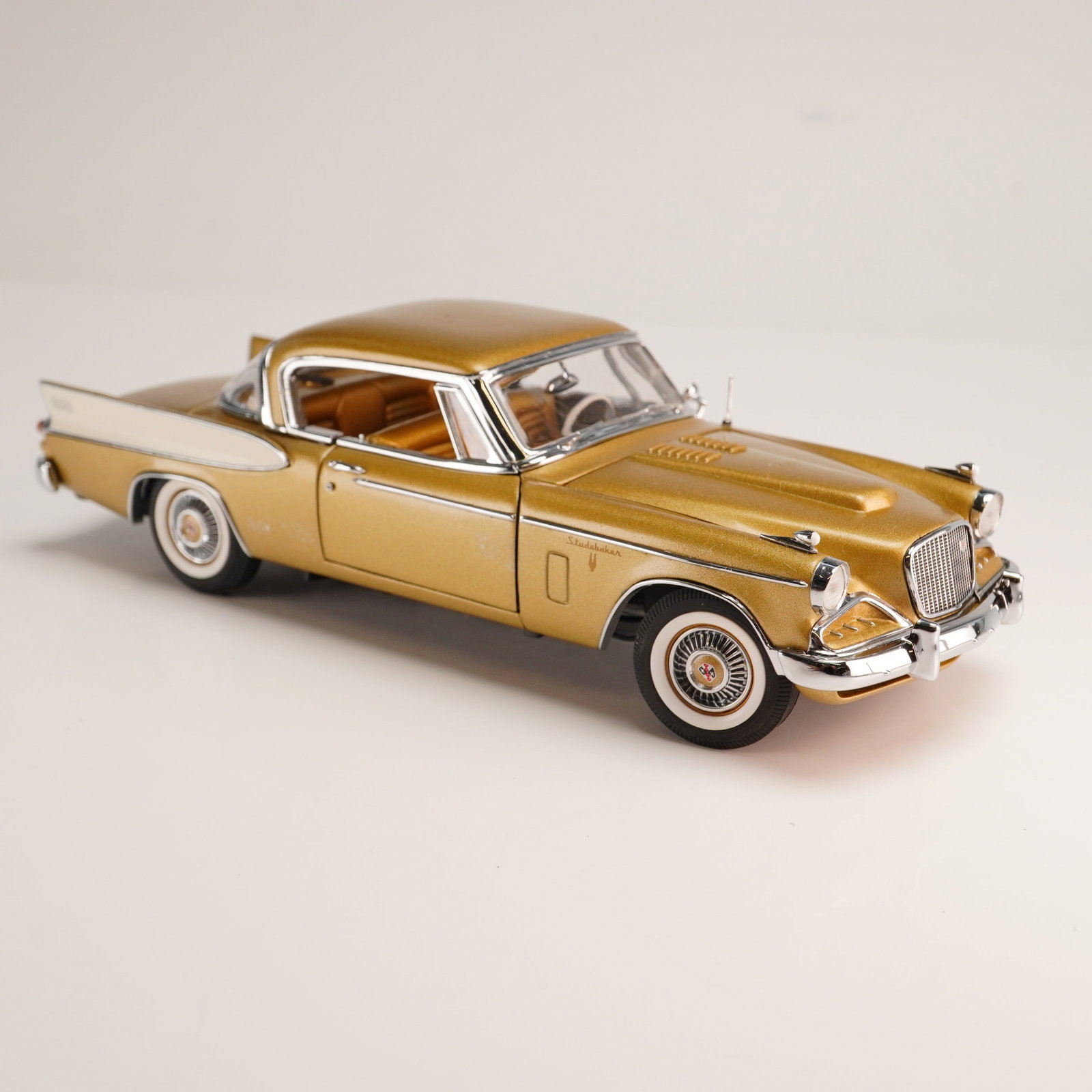 The Danbury Mint Model Car, 1957 Golden Hawk Studebaker: This lot features a 1:24 scale die-cast model replica from the Danbury Mint Classic Cars Collection, representing a 1957 Studebaker Golden Hawk. The vehicle is finished in a period-correct two-tone Ti