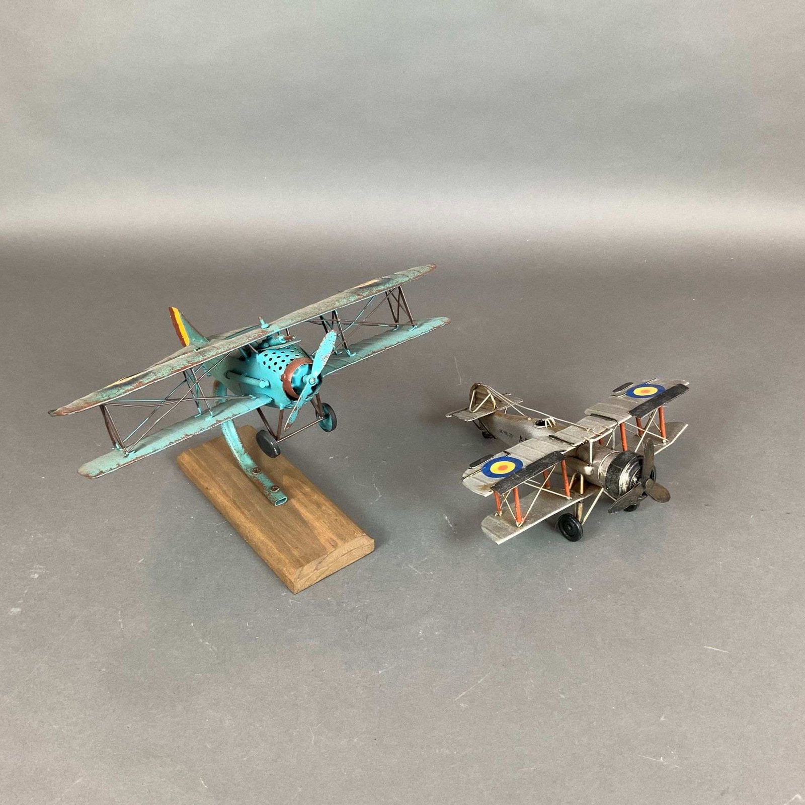 2pc British Royal Air Force Style Biplane Aircraft Models: This lot consists of a pair of British Airforce style aircraft models, constructed from painted sheet metal and designed as contemporary decorative collectibles with a vintage aesthetic. These items a