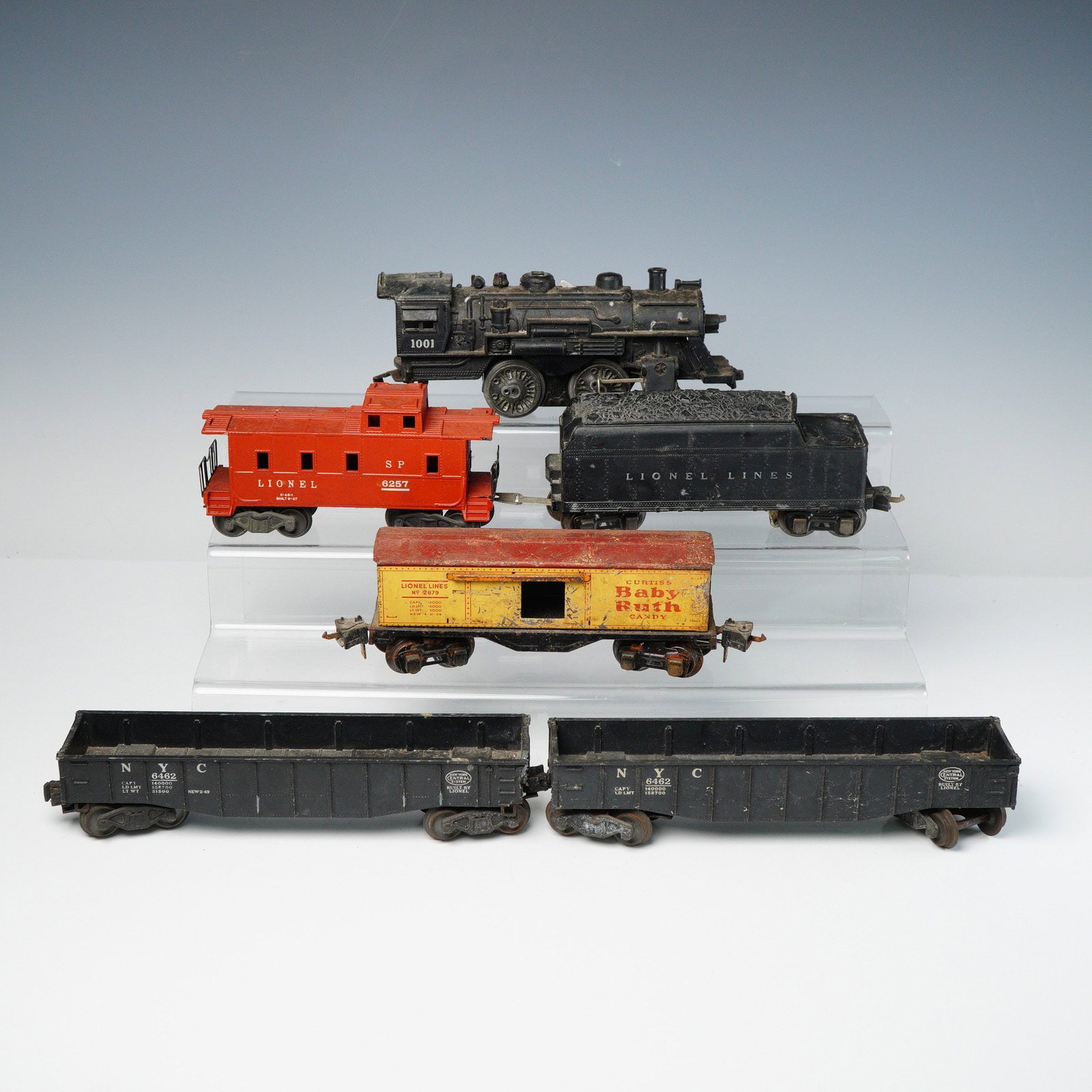 6pc Lionel O-Gauge Train Components: A collection of six vintage Lionel O-gauge train components, constructed primarily of die-cast metal and tinplate. The lot includes one black steam locomotive marked "1001," which bears an internal pl