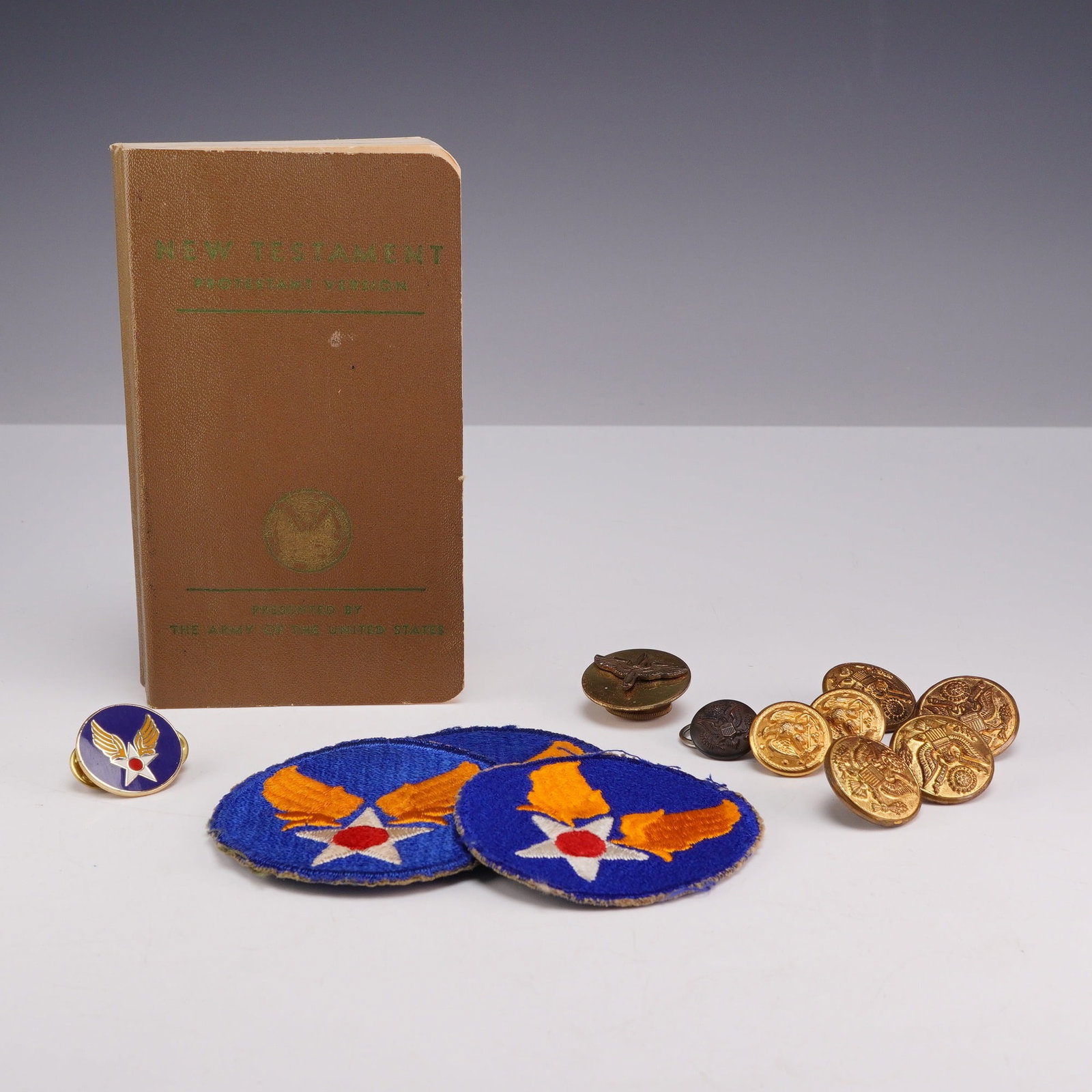 13pc Collection of WWII US Army Air Forces including 1941 New Testament, Jacket Buttons, Patches,: A 13-piece collection of WWII-era United States Army Air Forces (USAAF) personal effects and uniform insignia. The group includes one pocket-sized Protestant version of the New Testament dated 1941.