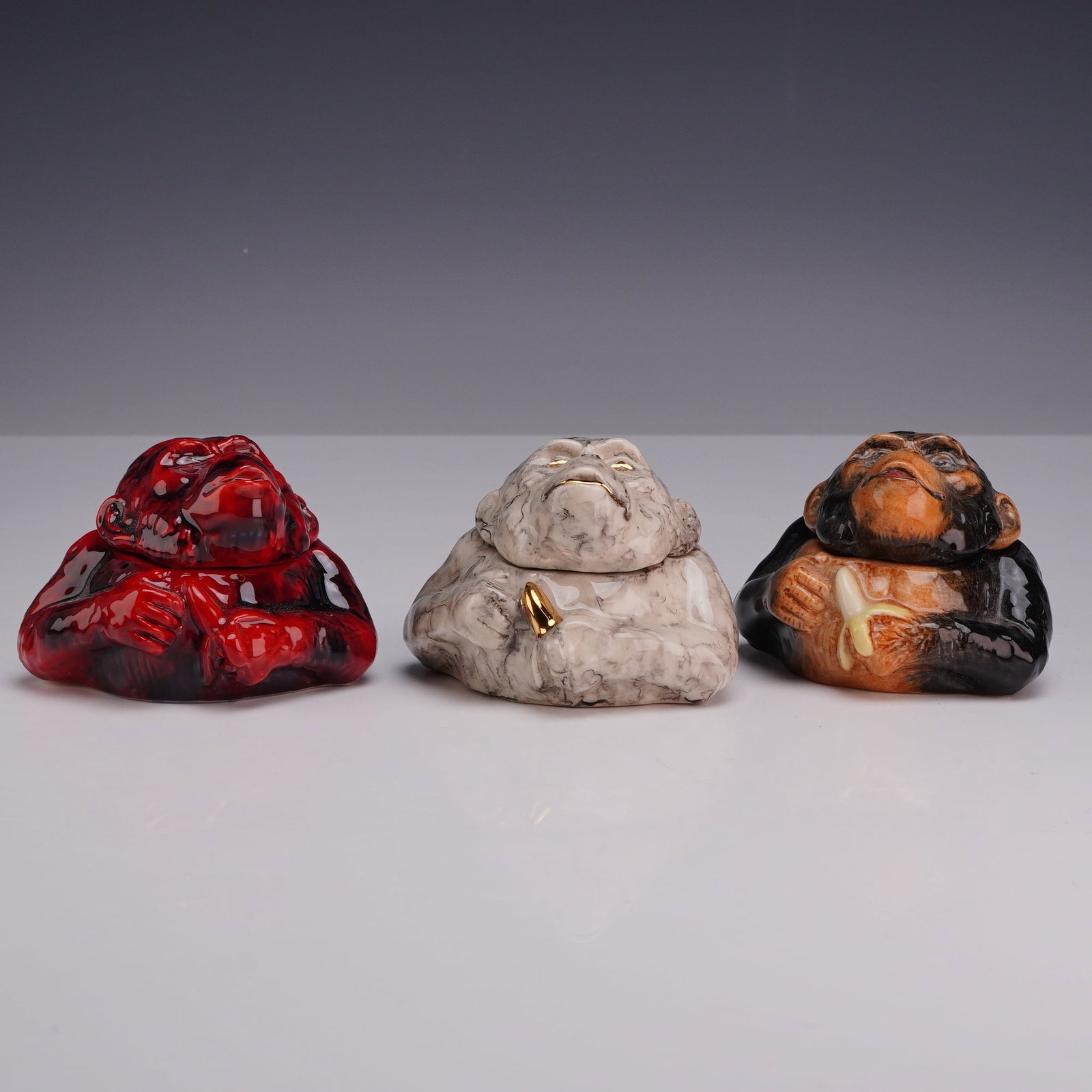 Three Kevin Francis Face Pots Charles Chimpanzee including Prototypes: This collection consists of three lidded miniature ceramic vessels from the Kevin Francis Face Pots series, each depicting a chimpanzee character titled Charles. Each piece is constructed with a