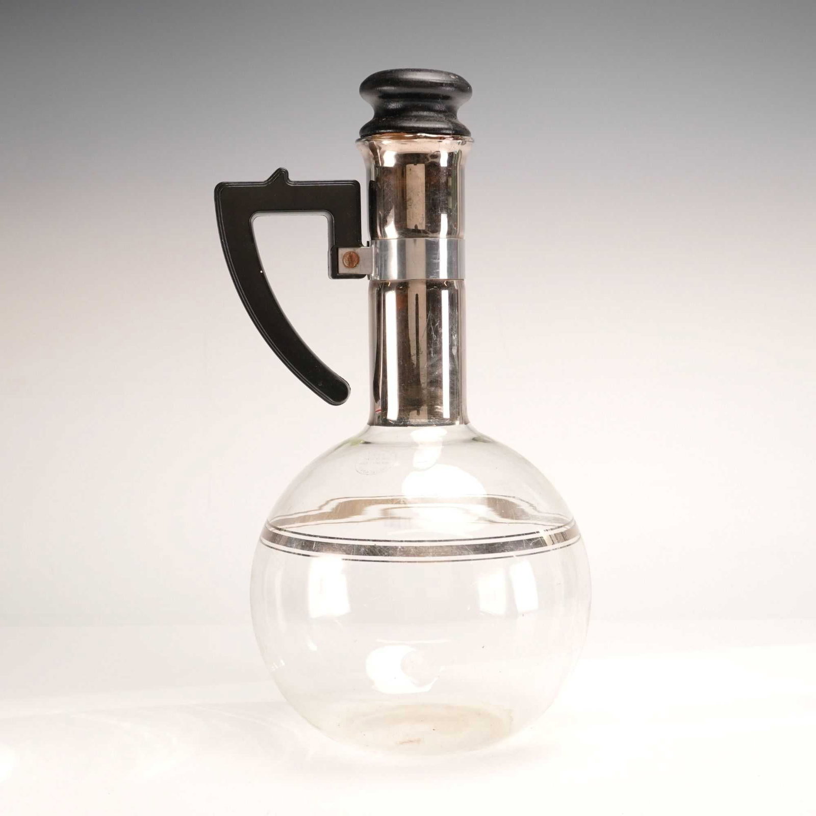 Inland Glass Works Art Deco XXX Hand Blown Glass and Silver Painted Carafe with Stopper: This Art Deco beverage carafe is produced by Inland Glass Works of Chicago, Illinois. It features a hand-blown heat-resistant clear glass spherical body accented with two horizontal silver-toned