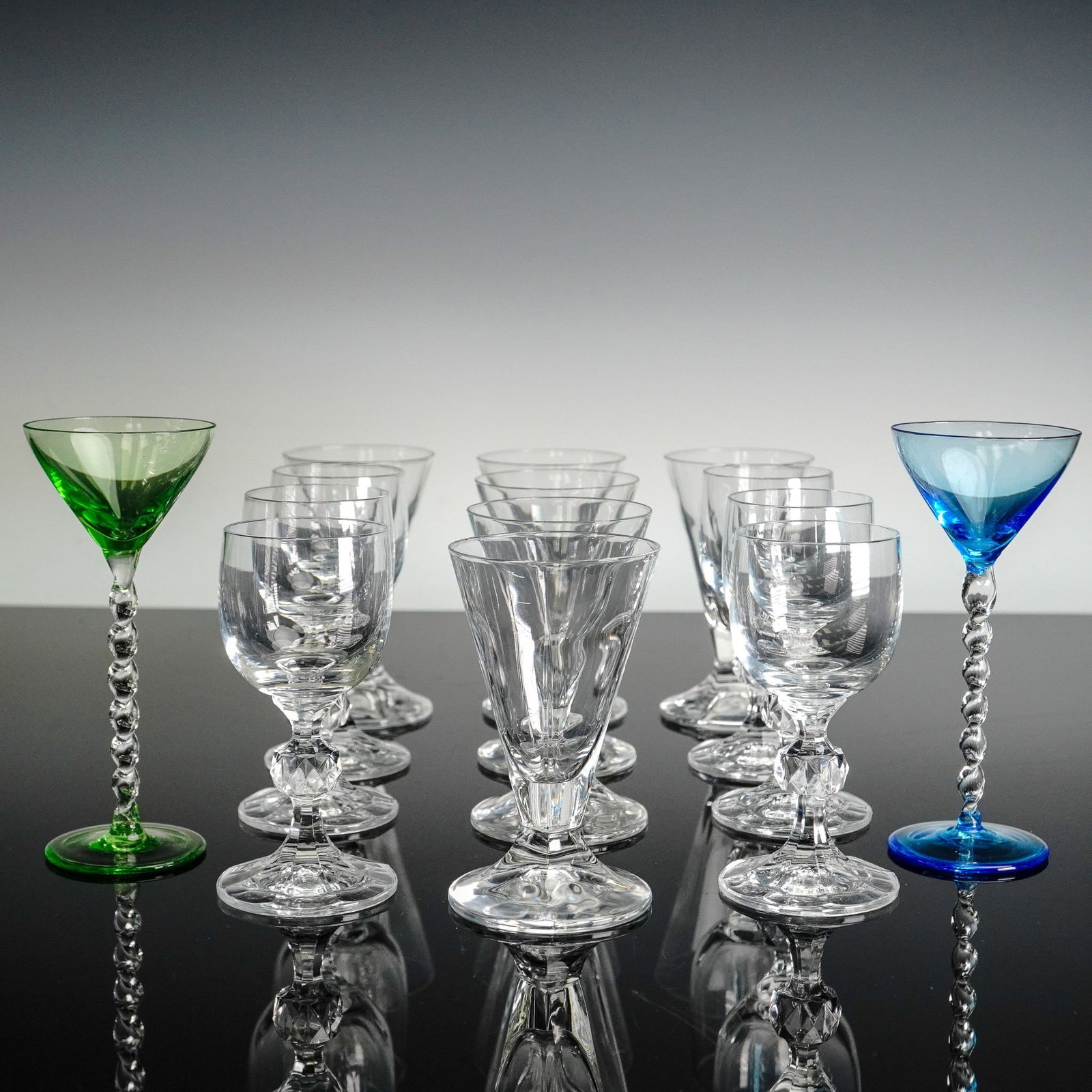 14pc Vintage Mixed Stemware Set with Colored Twist Stems: This elegant 14-piece vintage stemware set includes a stunning mix of clear and colored glasses featuring various stem designs. Among the collection are three clear goblets with faceted knop stems, th