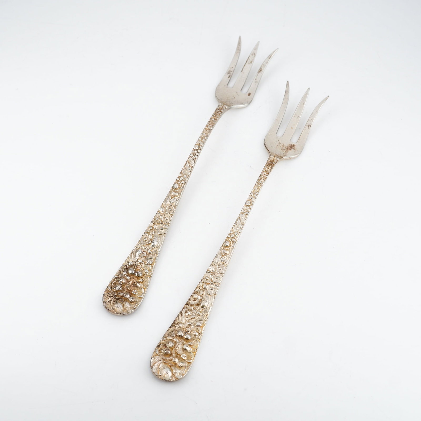 2pc Kirk Stieff Sterling Silver Cocktail Forks, Stieff Rose: Matched pair of cocktail forks rendered in the classic Stieff Rose design introduced in 1892. Each fork features a sterling silver handle with richly detailed floral repousse work in traditional