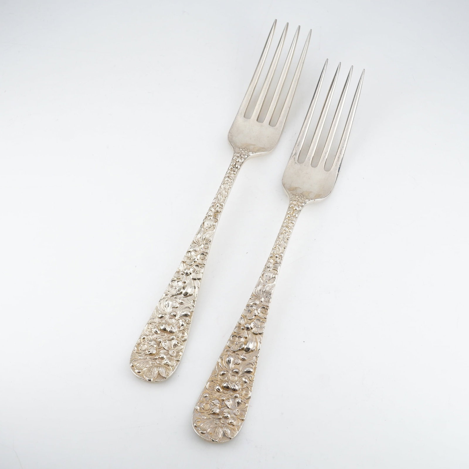 2pc Kirk Stieff Sterling Silver Forks, Stieff Rose: Two dinner forks in the timeless "Stieff Rose" pattern by Kirk Stieff, introduced in 1892. Each features a sterling silver handle with richly detailed floral repousse ornamentation in raised relief.