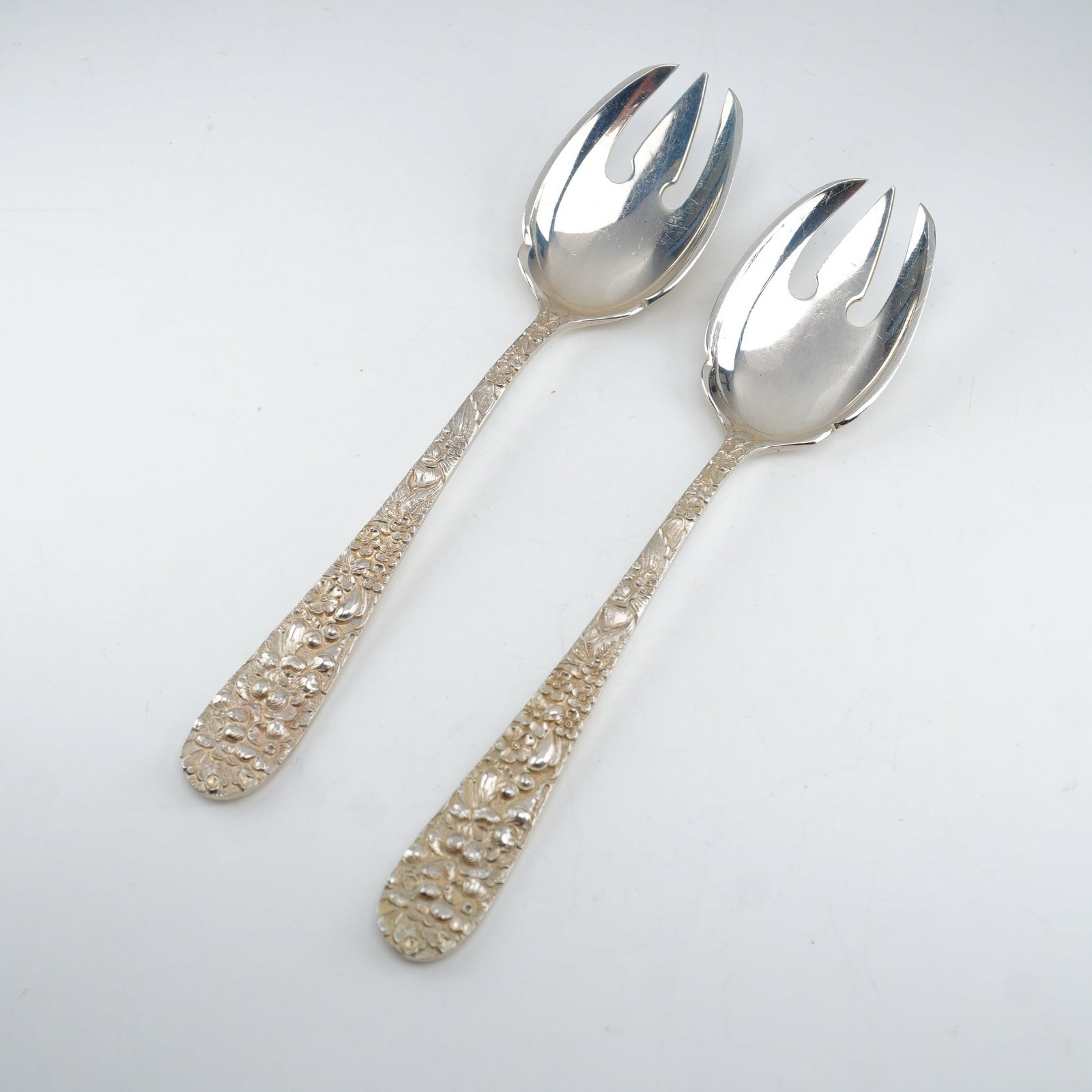 2pc Kirk Stieff Sterling Silver Ice Cream Forks, Stieff Rose: Each fork displays a finely crafted sterling handle with elaborate floral repousse ornamentation, executed in the traditional raised relief style introduced in 1892. Marked "Sterling Stieff."