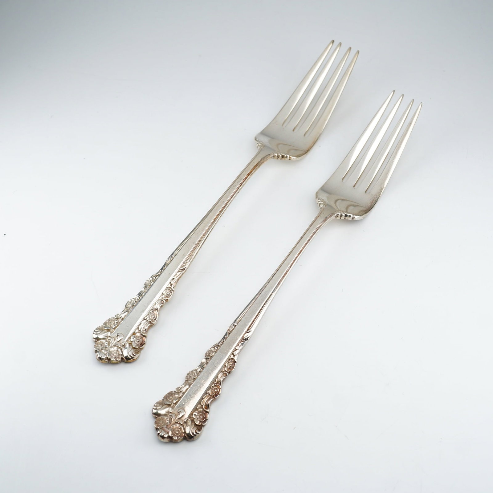2pc Lunt Sterling Silver Dinner Forks, Belle Meade: A pair of sterling silver dinner forks in the "Belle Meade" pattern by Lunt Silversmiths, produced from 1967 to 1997. Each fork features an ornate Rococo-inspired design with relief-molded floral