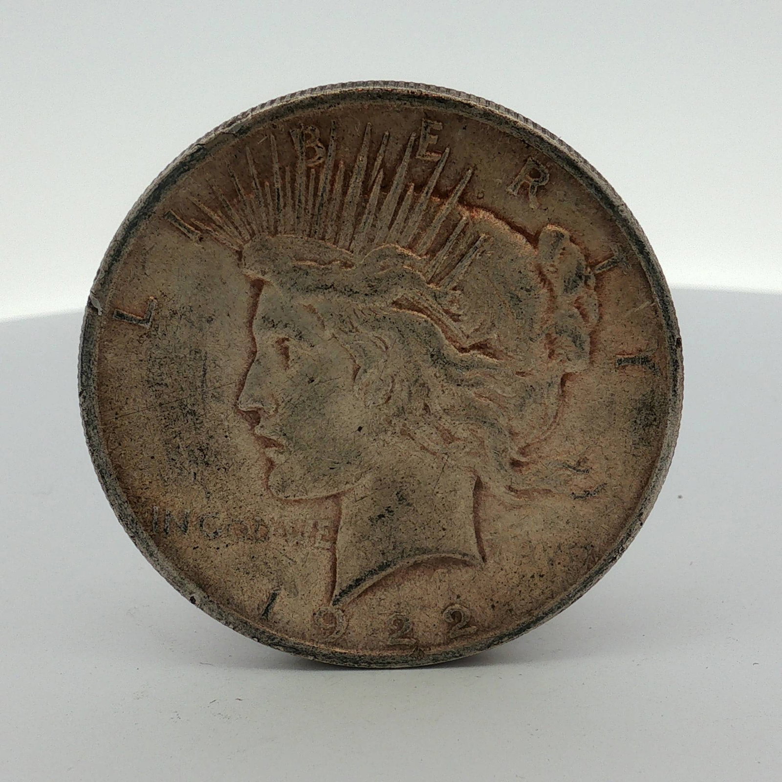 1922 US Peace Silver Dollar: A 1922 US Peace silver dollar struck at the Philadelphia Mint. The coin is composed of 0.900 silver and 0.100 copper. This Peace dollar features the standard designs of Anthony de Francisci and
