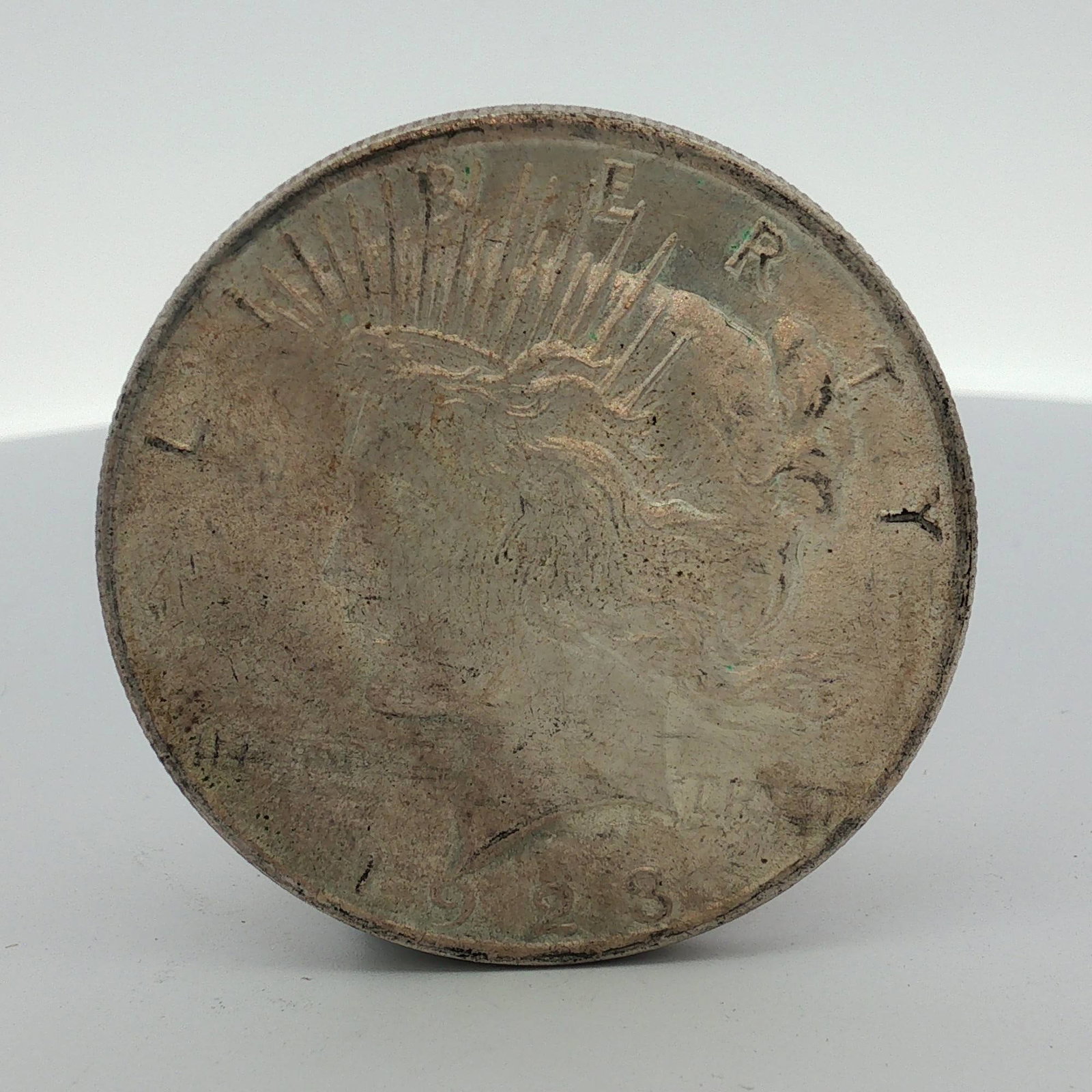 1923 US Silver Peace Dollar: This 1923 US Silver Peace Dollar is a Philadelphia Mint issue, indicated by the absence of a mint mark. Composed of 90 percent silver and 10 percent copper, the coin features the standard Peace Dollar