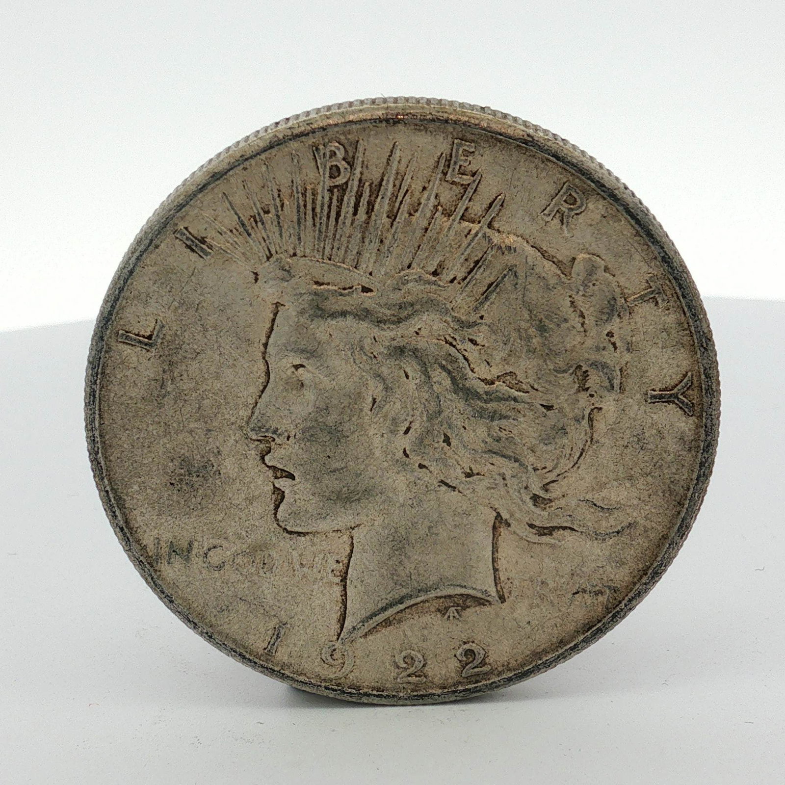 US 1922 Peace Silver Dollar: A 1922 US Peace silver dollar struck at the Philadelphia Mint in 90 percent silver. The coin features the standard Peace dollar obverse and reverse designs by Anthony de Francisci. The designer's AF m