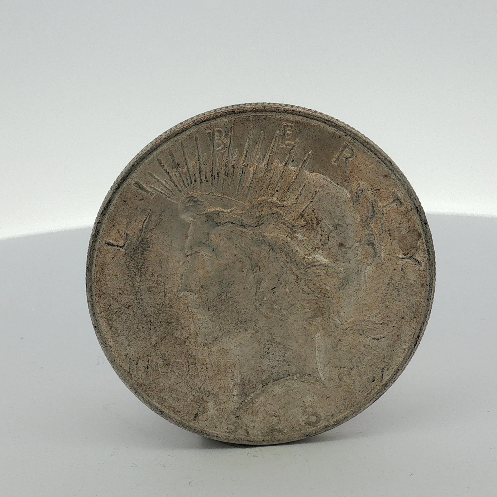 US 1923 Peace Silver Dollar: This is a US 1923 Peace silver dollar. The coin is struck in .900 fine silver. It features the standard Peace dollar design on the obverse and reverse. The absence of a mint mark on the reverse indica