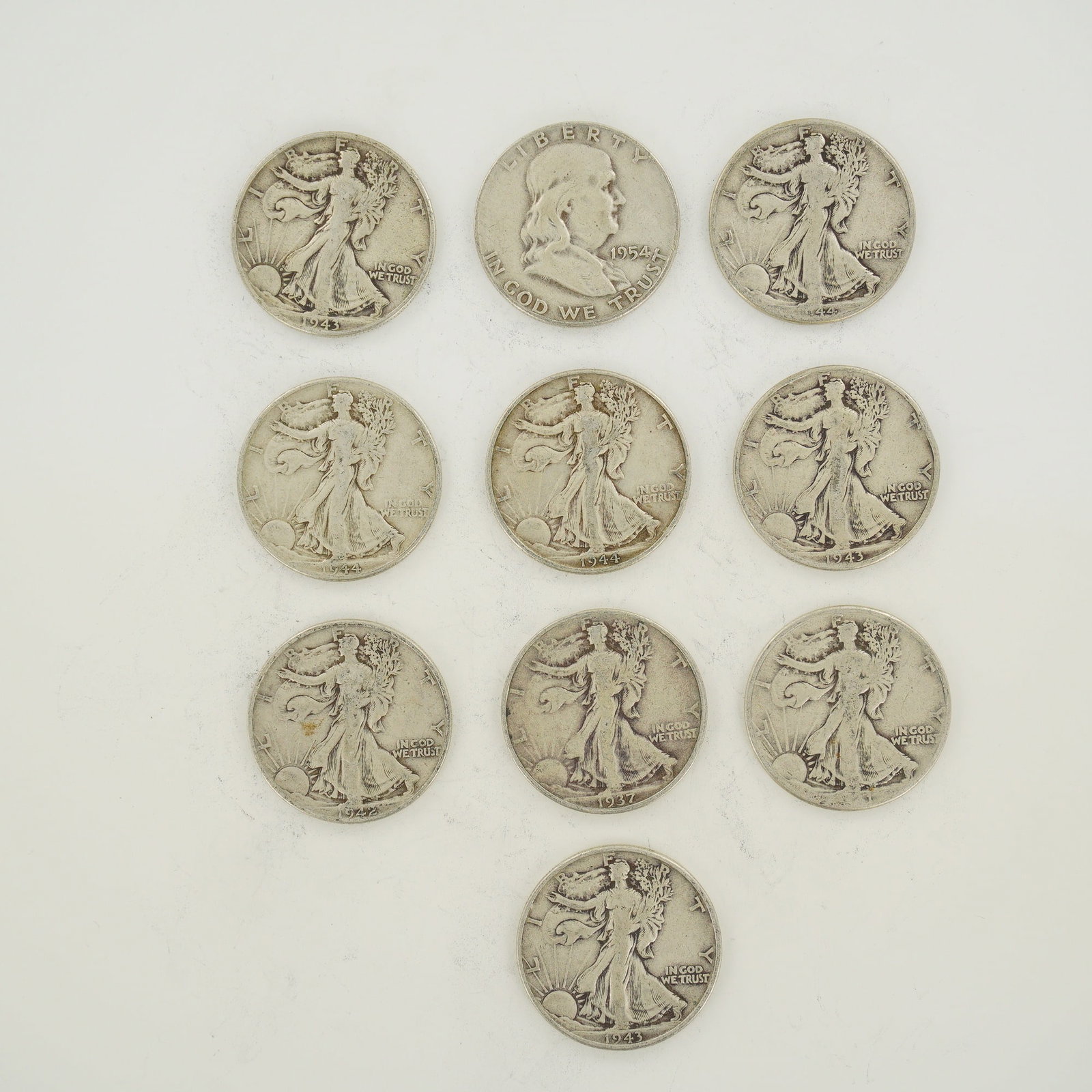 A Collection of US Silver Half Dollars Including Walking Liberty and Franklin Types: A collection of US silver half dollars comprising one Franklin half dollar and several Walking Liberty half dollars. The Franklin half dollar is dated 1954 and is cataloged as KM 199. The Walking Libe