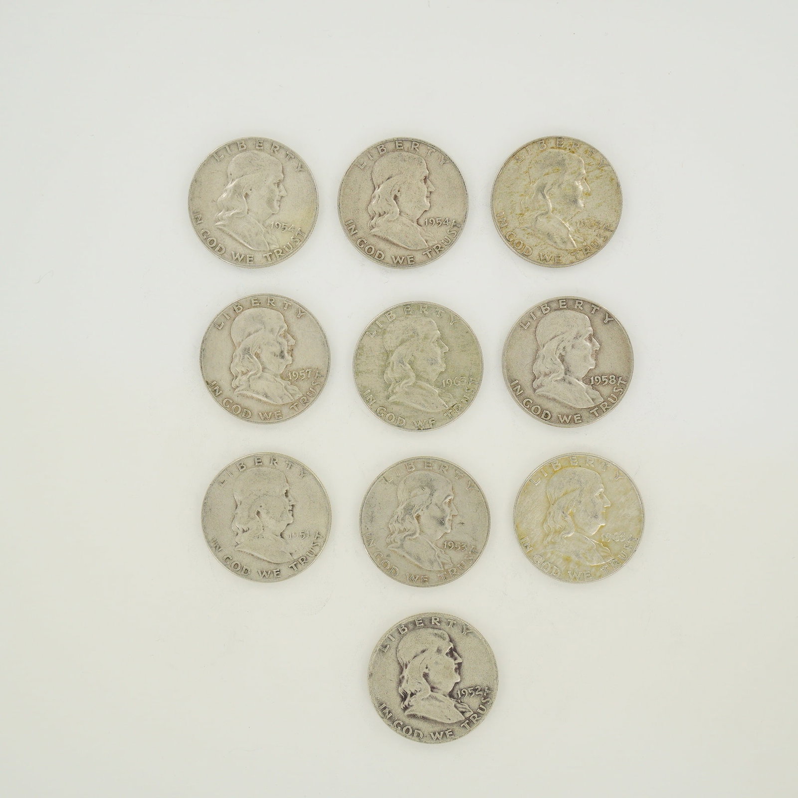A Group of US Ben Franklin 90% Silver Half Dollars: A group of US Ben Franklin half dollars composed of 90 percent silver. These coins feature the Franklin obverse and the Liberty Bell reverse with reeded edges. The assortment includes various dates