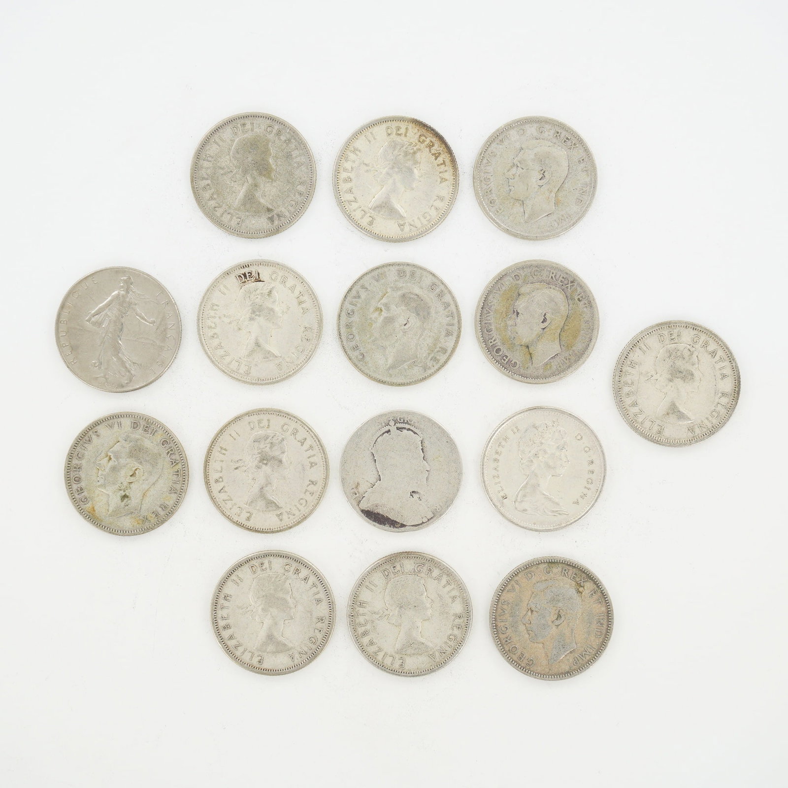 A Collection of CA and FR Coins: This mixed date bag of coins features CA 25-cent pieces and a single FR 1-franc piece. The CA quarters display the Caribou reverse design. Obverse portraits include Elizabeth II, George VI, and George