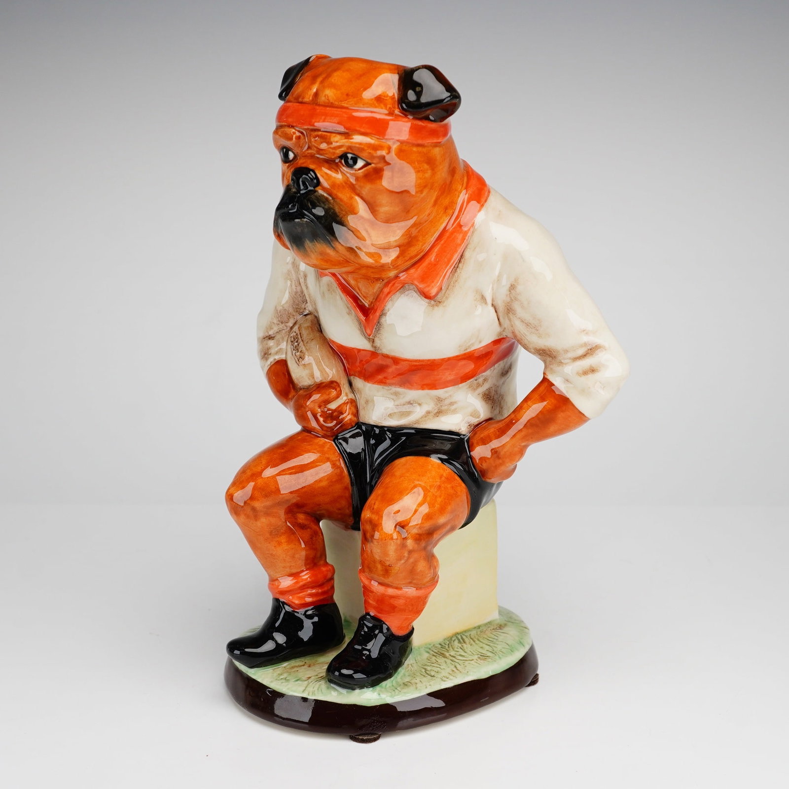 Kevin Francis Limited Edition Ceramic Character Jug, The Bulldog Rugby Player: This hand painted ceramic character jug, titled The Bulldog Rugby Player, was produced by Peggy Davies Ceramics for Kevin Francis. The piece features an anthropomorphic bulldog seated on a square bloc