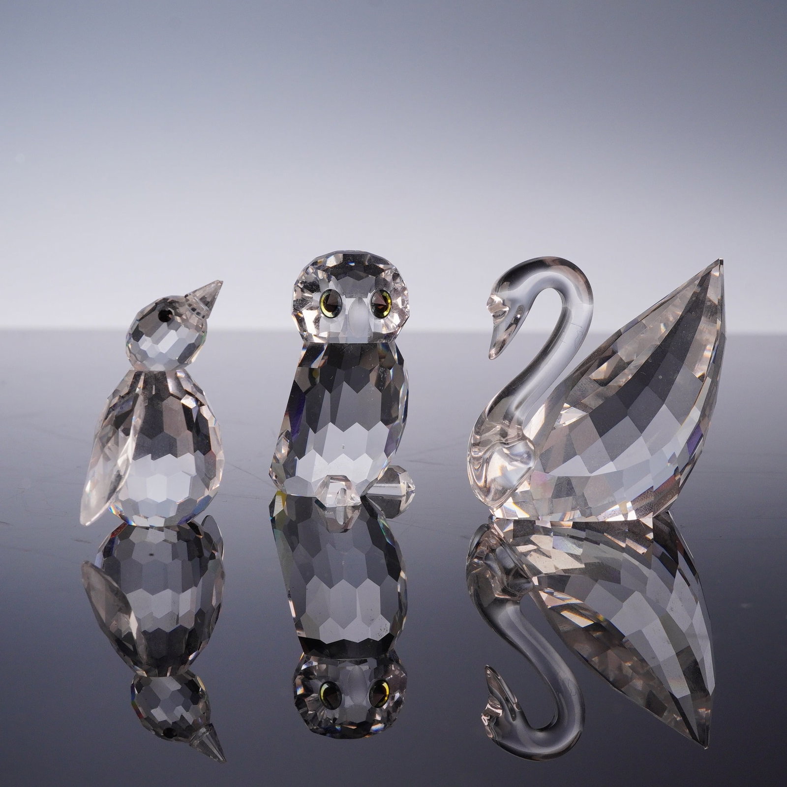 3pc Swarovski Crystal Bird Figurines Including a Penguin, Owl, and Swan: A set of three faceted clear lead crystal bird figurines produced by Swarovski as a New Membership Welcome Gift for the Swarovski Crystal Society (SCS). This collection consists of a baby penguin with