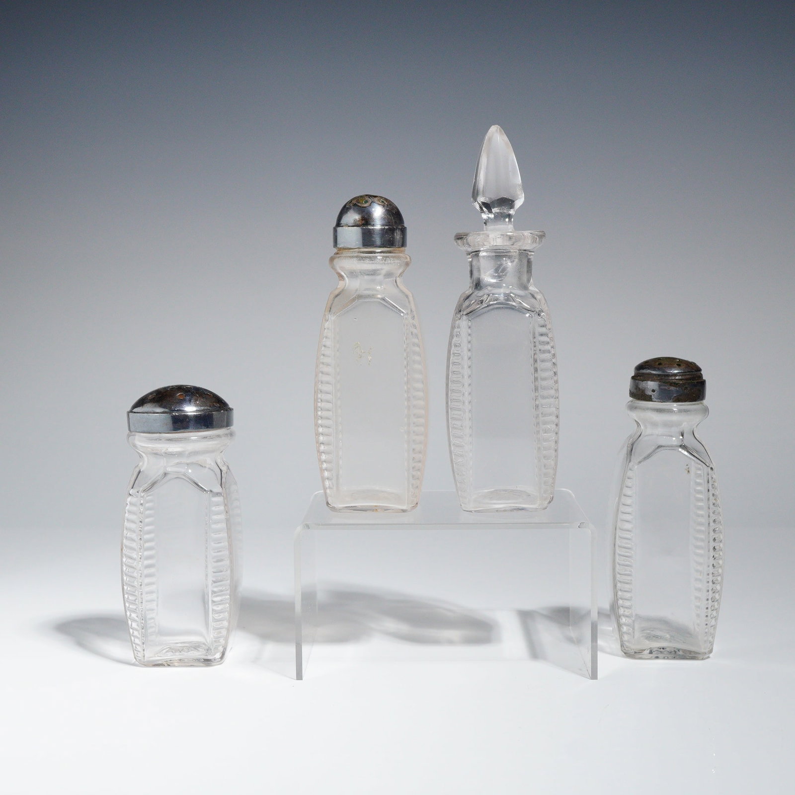 A Collection of Four American Pressed Glass Cruetware Pieces: A collection of four pieces of pressed glass cruetware, consistent with late 19th to early 20th-century American manufacture. The 4pc set comprises three salt shakers and one small oil cruet. The
