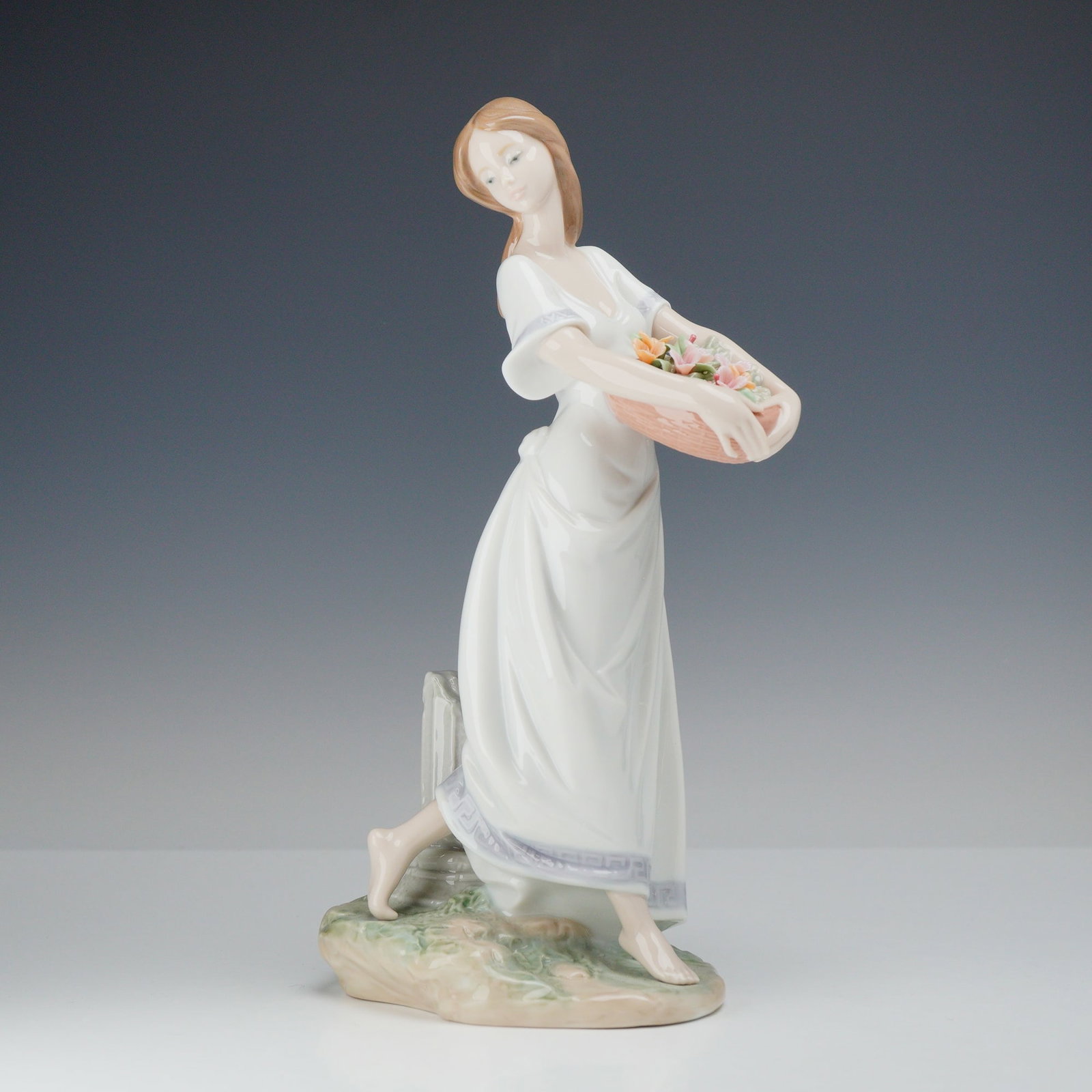Lladro Gardens of Athens Glazed Porcelain Figurine Model 7704: A Lladro glazed porcelain figurine titled Gardens of Athens, model number 7704. The piece depicts a young woman in a walking pose, dressed in a long, flowing white gown. The dress features a lavender 