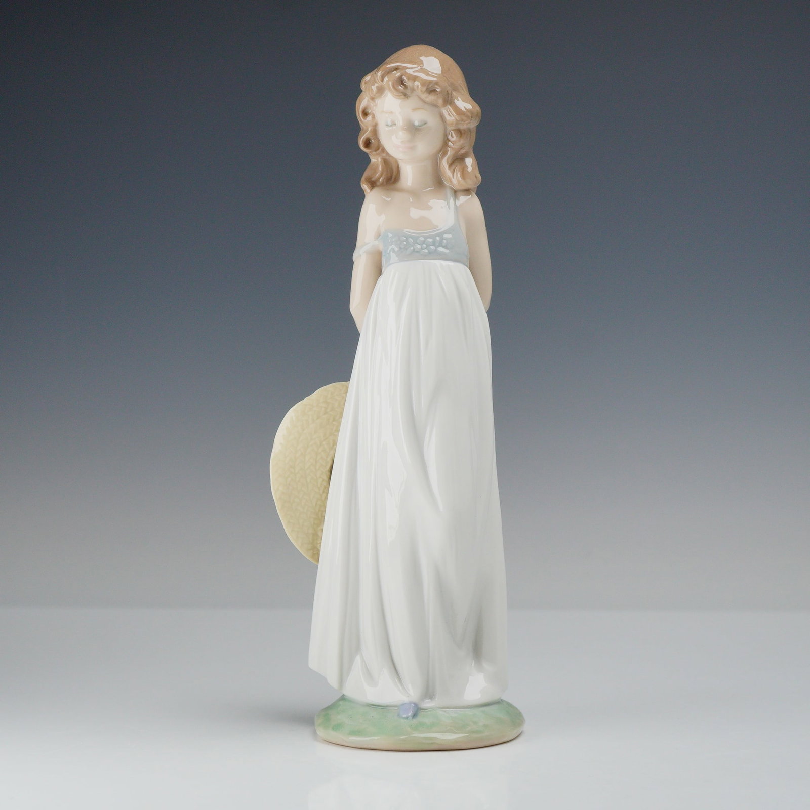 Lladro Porcelain Figurine Natural Beauty Model 8114: A Lladro glazed porcelain figurine titled Natural Beauty, model number 8114. The figurine depicts a young girl in a contemplative standing pose, looking slightly downward. She has long, wavy brown hai