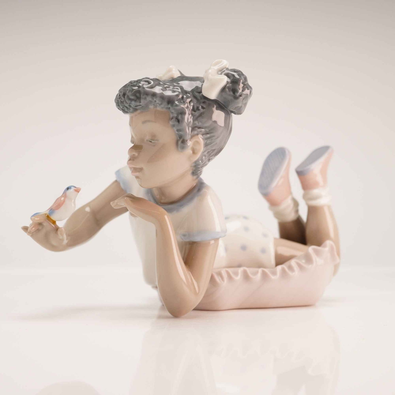 Lladro Porcelain Figurine, 1005837 Sing With Me: This glazed porcelain figurine, titled Sing with Me, is a product of Lladro, manufactured in Spain. Designed by sculptor Jose Luis Alvarez, the piece depicts a young girl with dark, curly hair accente