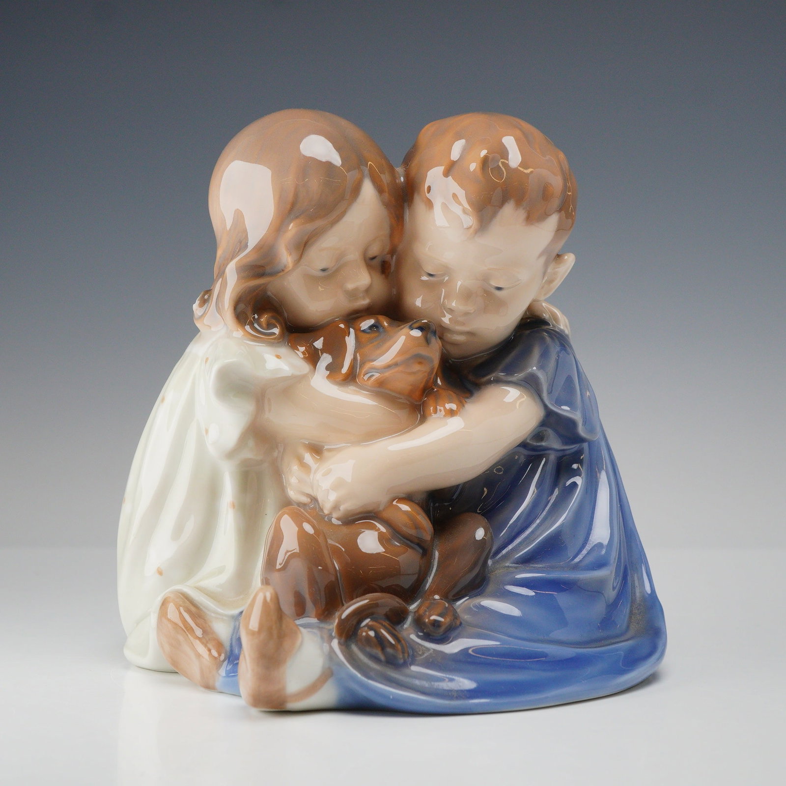 Royal Copenhagen Porcelain Figurine, Children with Dog 707: A Royal Copenhagen polychrome glazed porcelain figurine, model number 707, often referred to as Brother and Sister or Children with Dog. Designed by Christian Thomsen, the sculpture depicts a young bo
