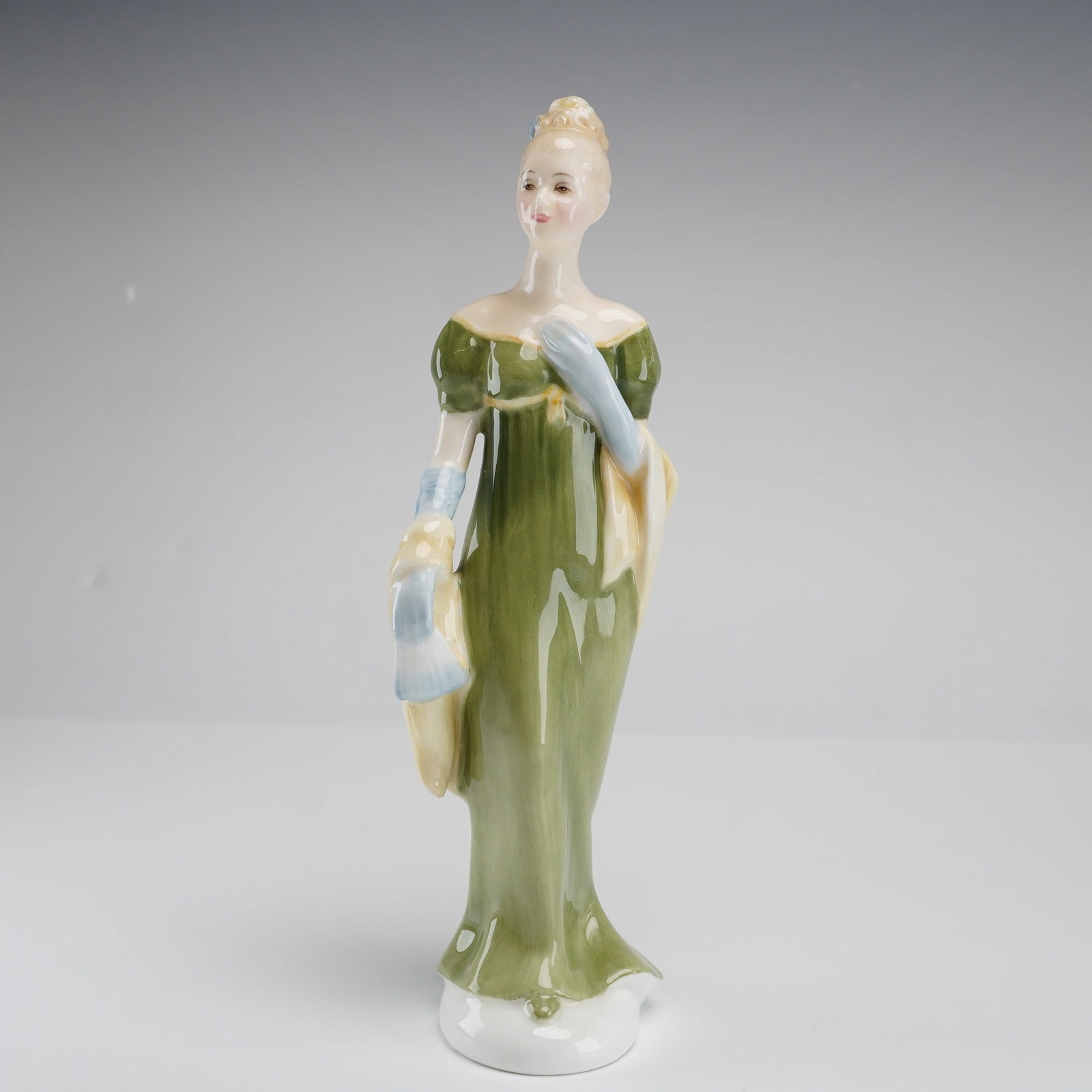 Royal Doulton Figurine Lorna HN2311: This Royal Doulton bone china figurine, titled Lorna (HN 2311), was designed by artist Peggy Davies and issued in 1964. The piece depicts a woman in an elegant, high-waisted Empire-style gown in olive