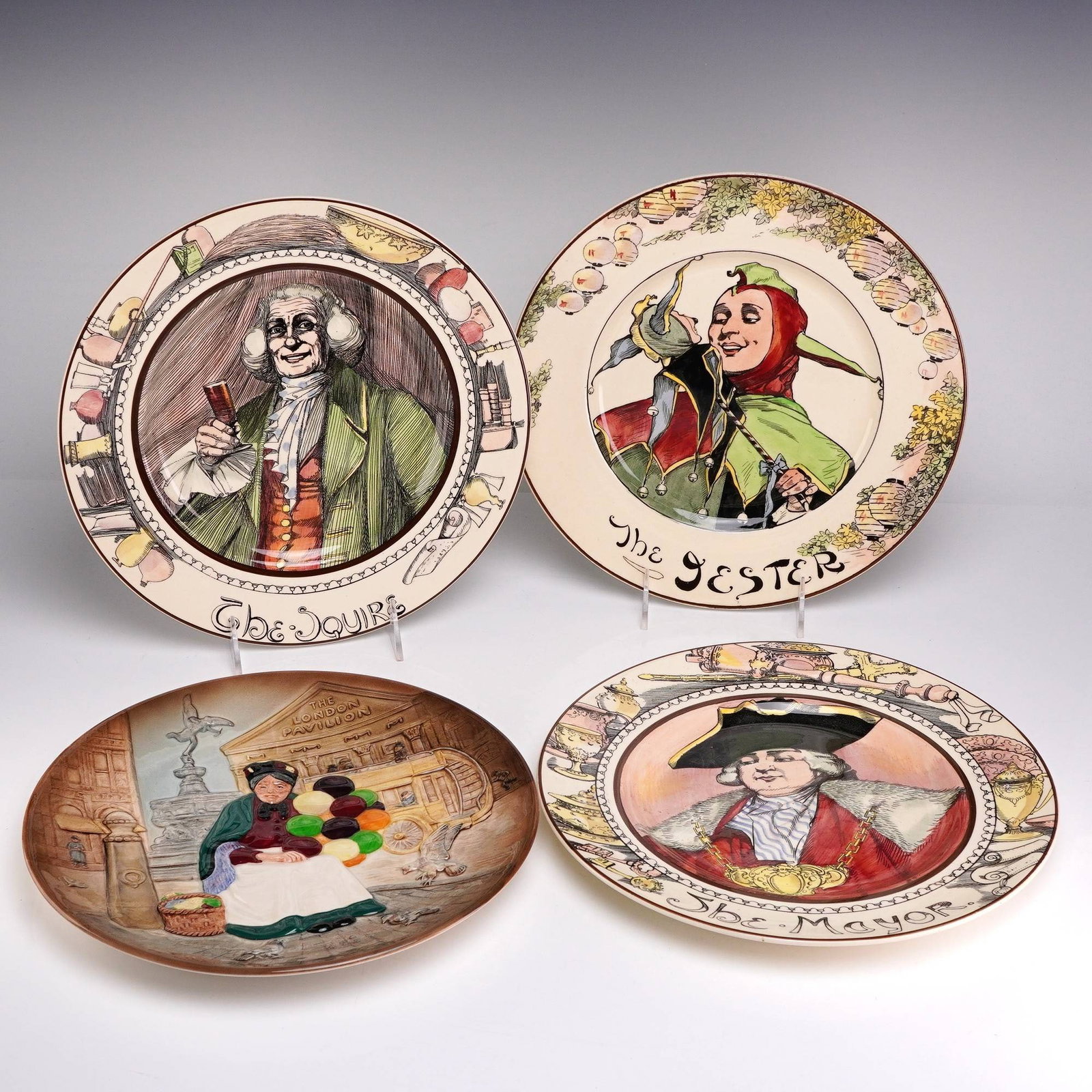 4pc Royal Doulton Ceramic Character Plates including The Old Balloon Seller and The Jester: A set of four Royal Doulton glazed earthenware character plates featuring polychrome transfer-printed designs with hand-painted colored highlights. The collection comprises the following subjects: The