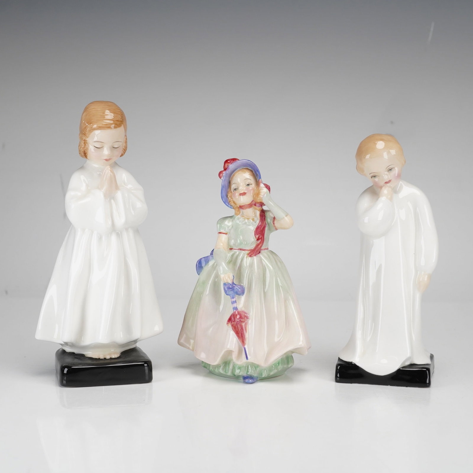 3pc Royal Doulton Bone China Figurines, Bedtime, Darling & Babie: A trio of Royal Doulton glazed bone china figurines. The collection includes the model Bedtime (HN 1978), featuring a child in a white nightgown with hands in prayer positioned on a square black base.