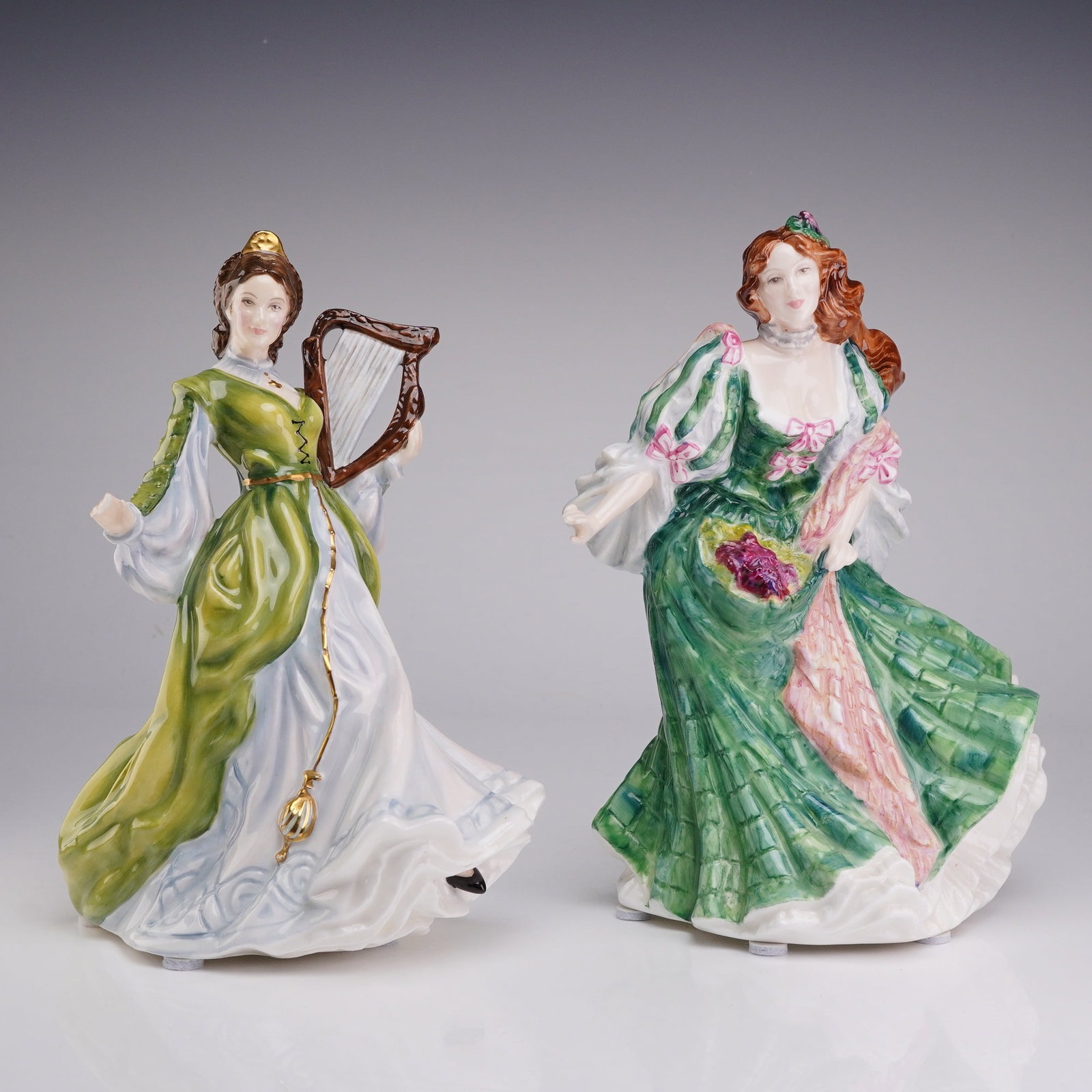 Two Royal Doulton Ladies of the British Isles Figurines, Ireland HN3628 and Scotland HN3629: This lot consists of two hand-painted bone china figurines from the Royal Doulton Ladies of the British Isles collection, modeled by Valerie Annand. The first figurine, Ireland (HN 3628), is depicted 