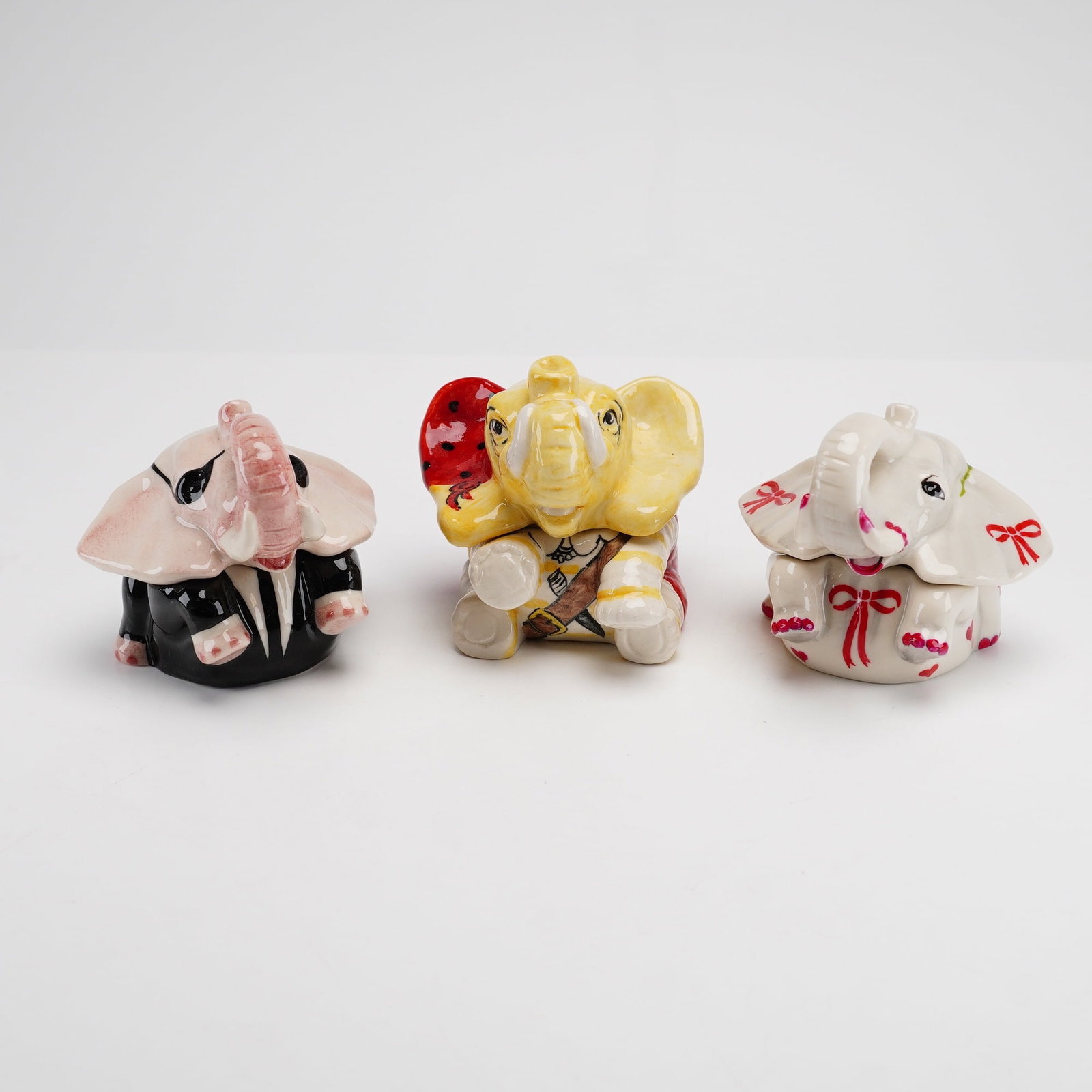 Three Kevin Francis Face Pots Elephant Trinket Boxes Including Pirate and Blues Brothers: This lot consists of three glazed trinket boxes from the Face Pots collection by Kevin Francis Ceramics, each designed in the form of a stylized elephant. The first elephant, identified as the Blues
