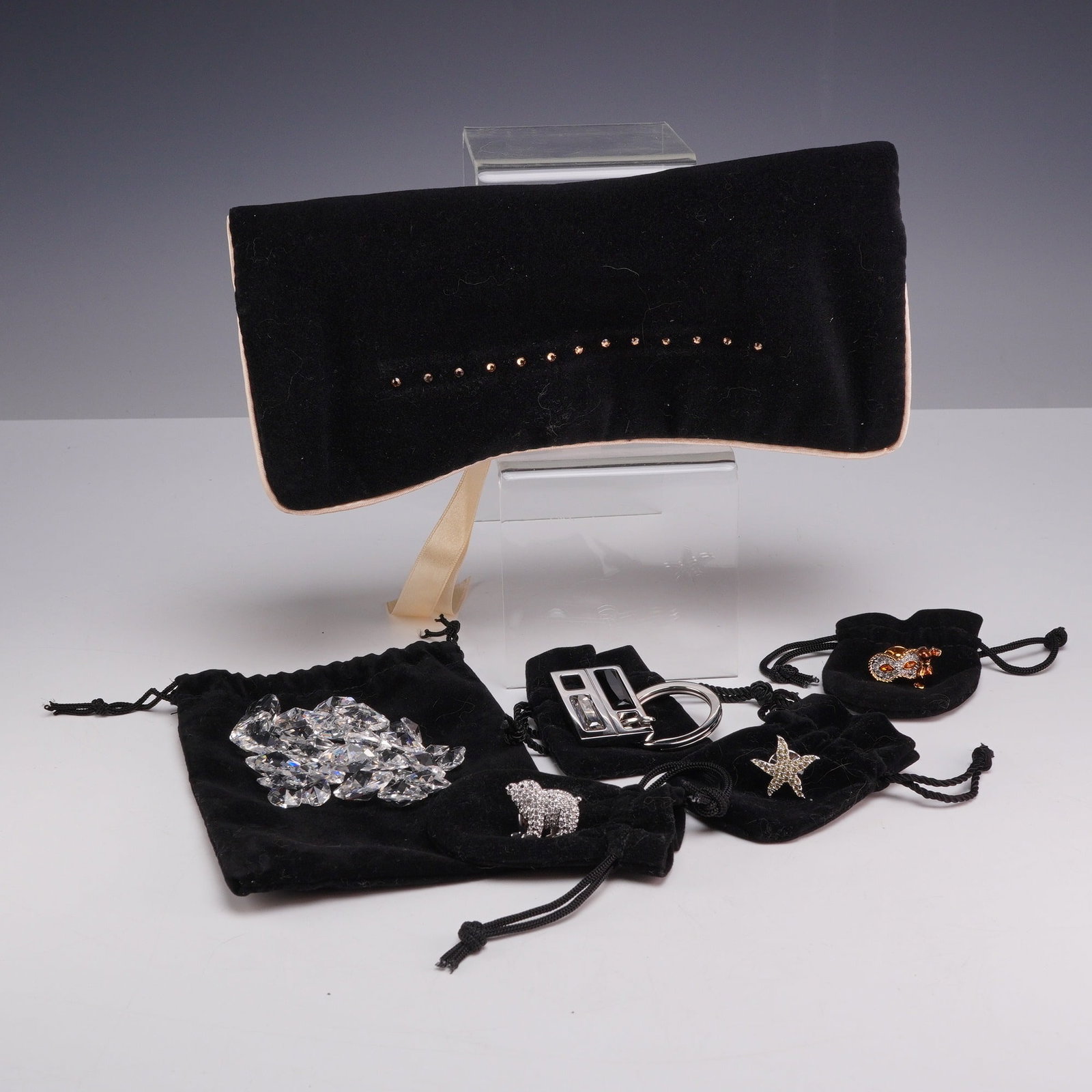 Collection of Six Swarovski Loose Crystals, Traveler's Jewelry Bag, Pins, and Keychain: This collection includes 37 pieces attributed to the luxury crystal manufacturer Swarovski, as indicated by the logo on the included presentation box. The lot is comprised of one traveler's jewelry