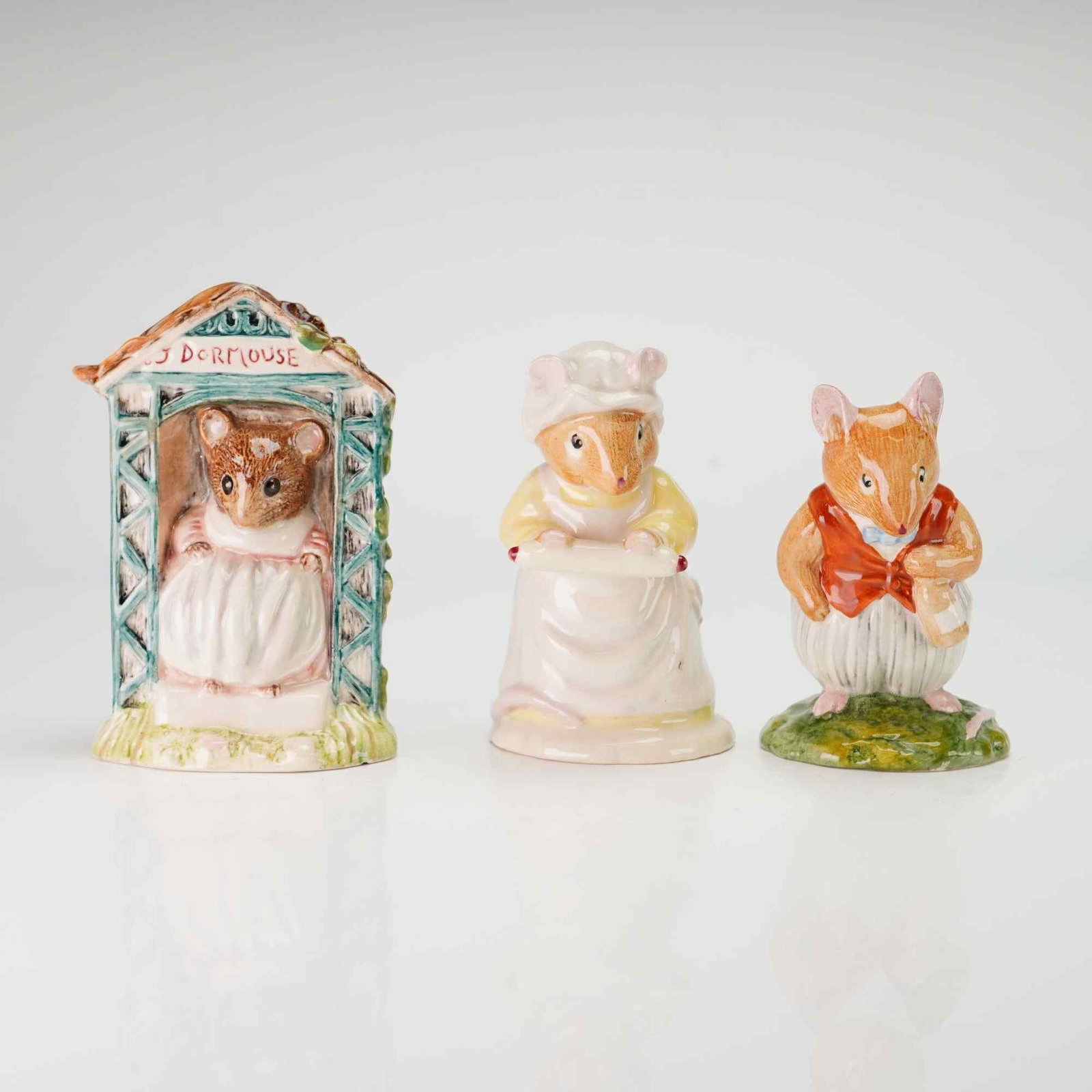 3pc Glazed Ceramic Figurines Including Two Royal Doulton Brambly Hedge and One Royal Albert Beatrix: This lot features a trio of glazed porcelain figurines depicting anthropomorphic mouse characters from children's literature. The collection includes two Royal Doulton Brambly Hedge figures and one Ro