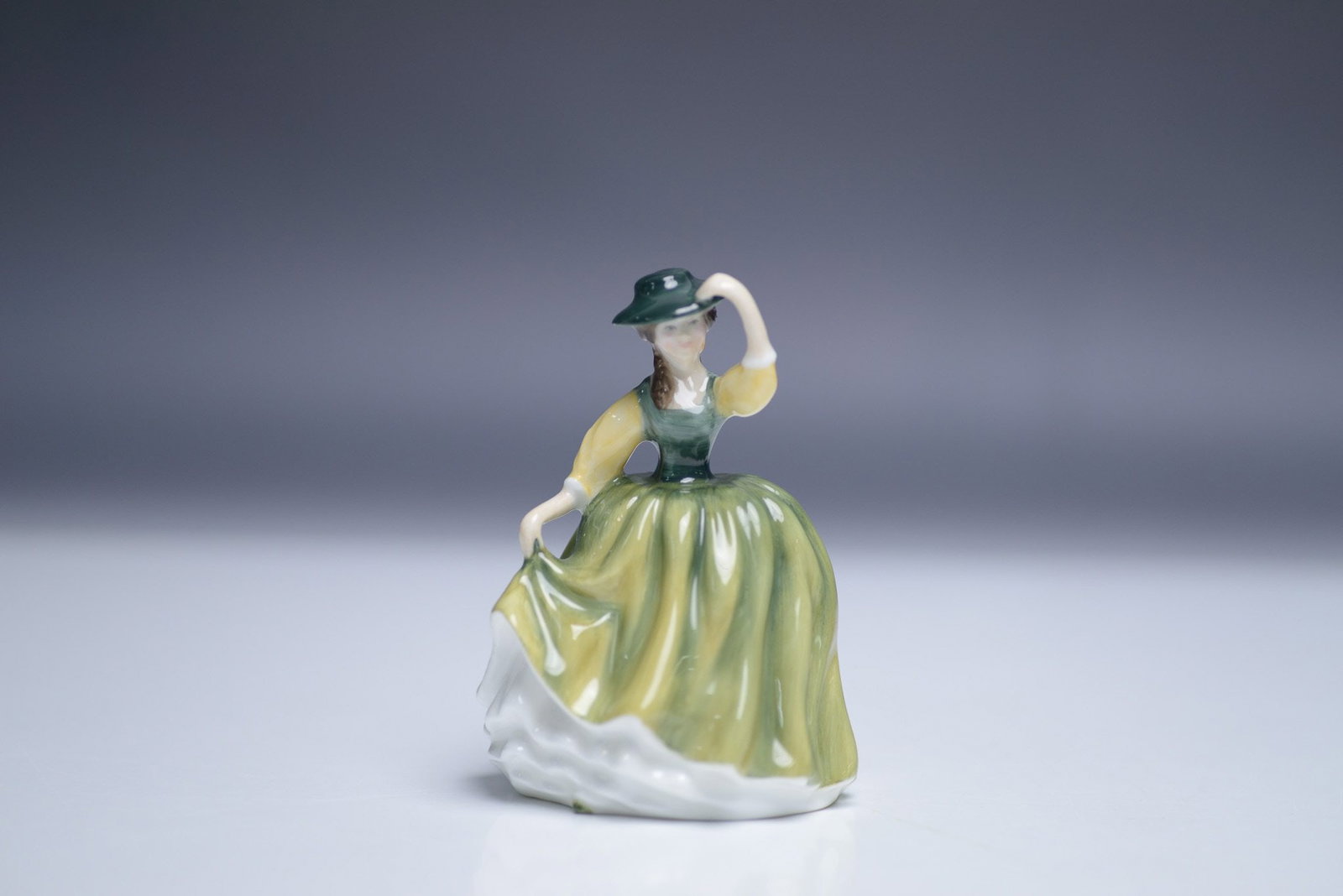 Royal Doulton Figurine, Buttercup HN3288: This Royal Doulton figurine, titled "Buttercup" (HN3288), was designed by Peggy Davies and measures 4"H. Crafted in fine china, it features a young woman in a green and yellow dress with delicate