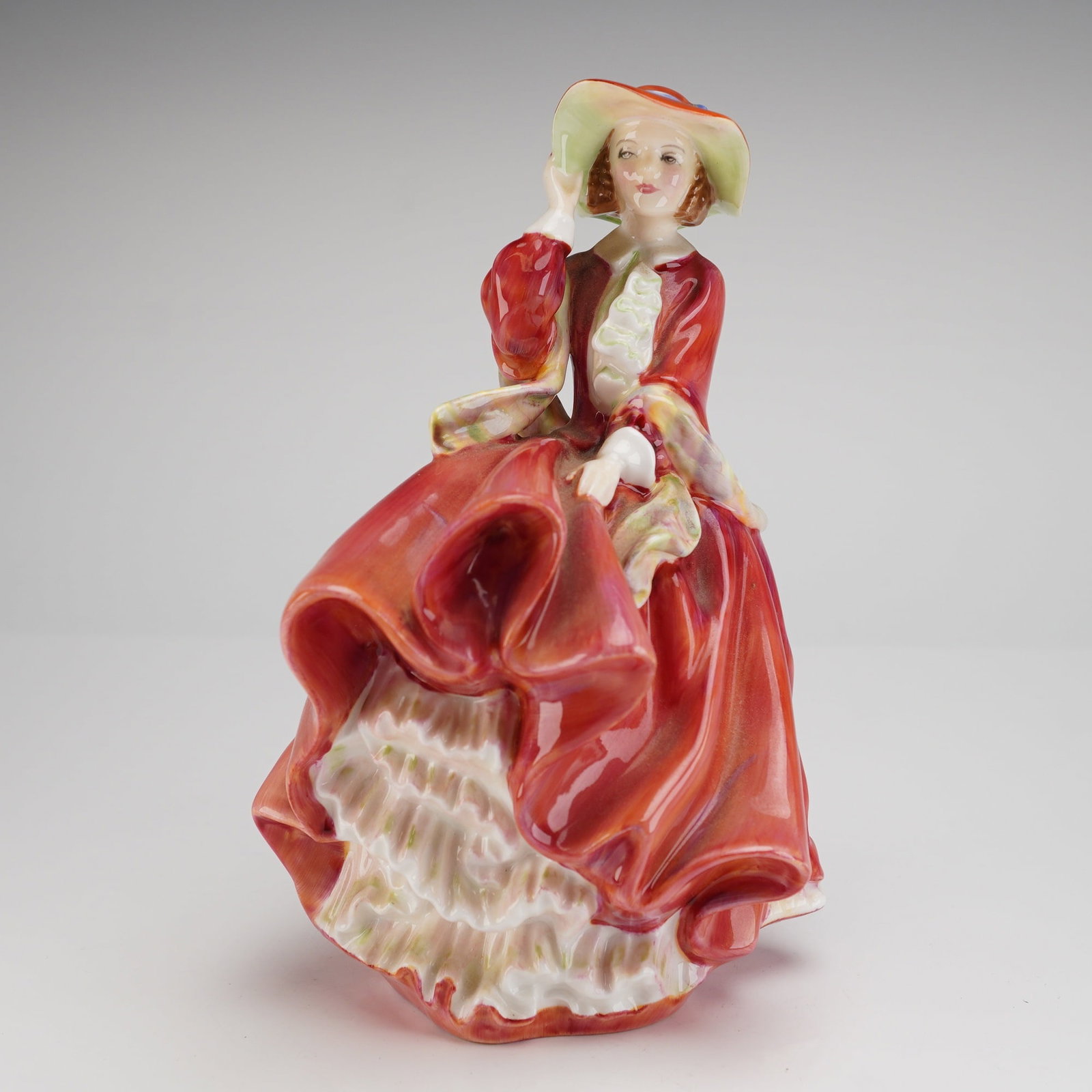 Royal Doulton Bone China Figurine Top O' The Hill HN 1834: A single glazed bone china figurine manufactured by Royal Doulton, titled Top O' The Hill, model number HN 1834. The figurine depicts a woman in a formal, flowing gown primarily decorated in a glossy 