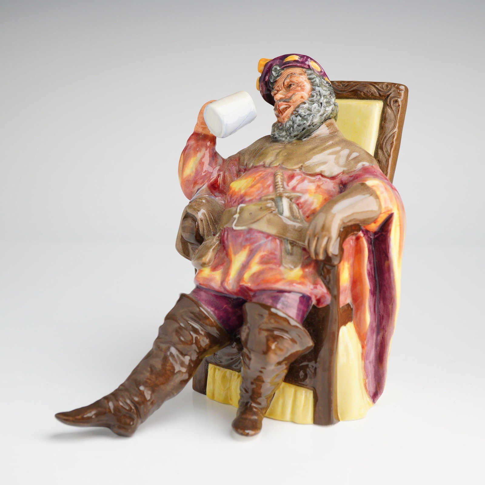 Royal Doulton The Foaming Quart HN2162 Figurine: This is a vintage Royal Doulton ceramic figurine titled The Foaming Quart, model number HN2162. The piece depicts a bearded male figure in historical dress, seated in a high-backed chair while raising